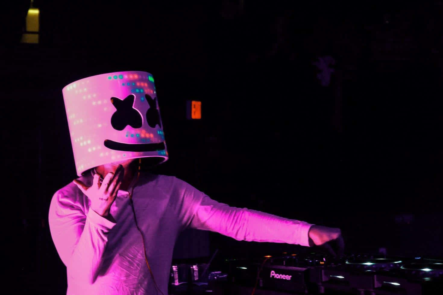 Marshmello 桌布 壁紙 — 一位DJ戴著發光的粉紅色棉花糖頭盔，在黑暗的夜店中於霓虹燈下混音。