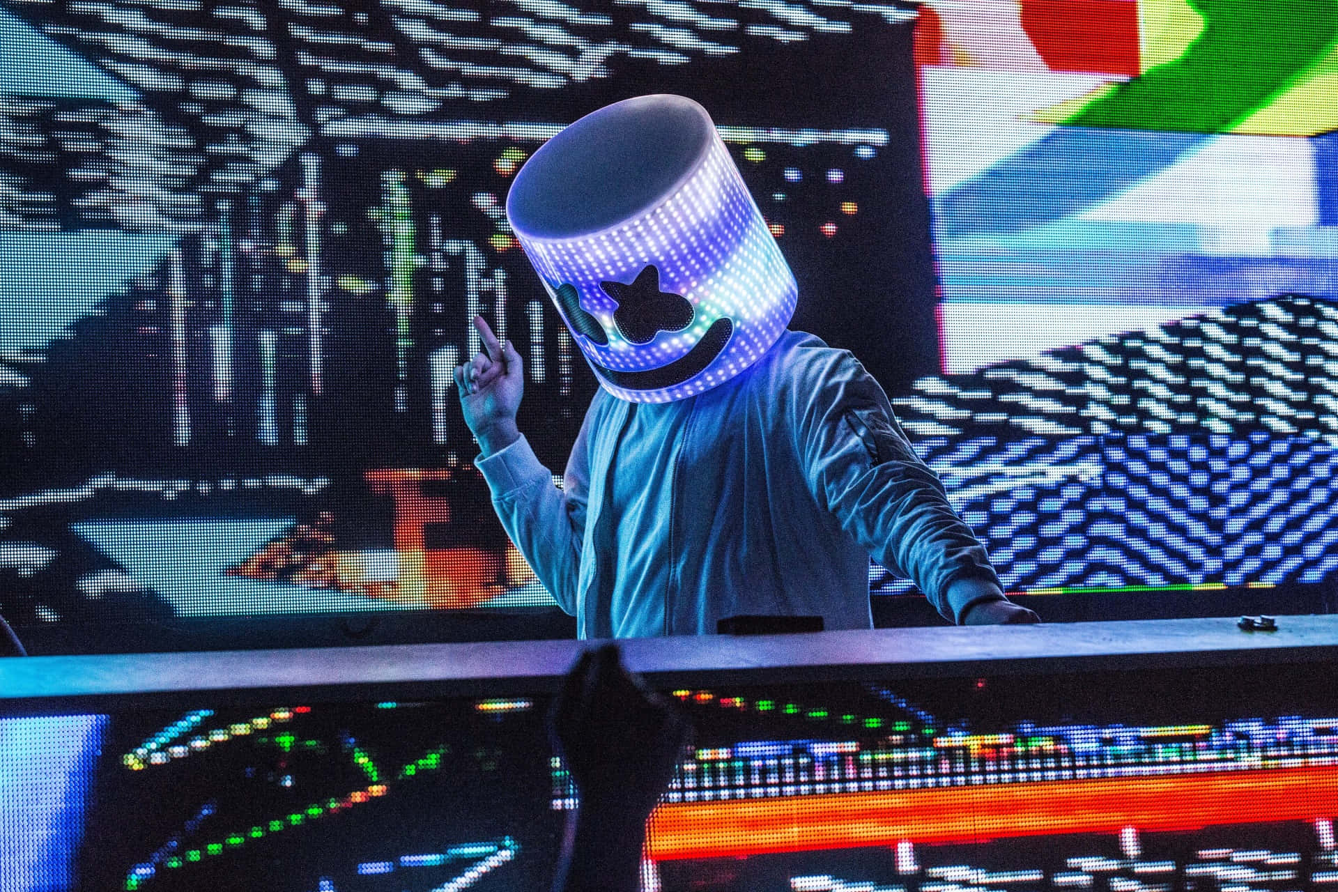 Marshmello 桌布 壁紙 — 一位DJ戴著發光的藍色LED棉花糖面具，在充滿活力的電子音樂節上表演，身後是色彩繽紛的數位螢幕。