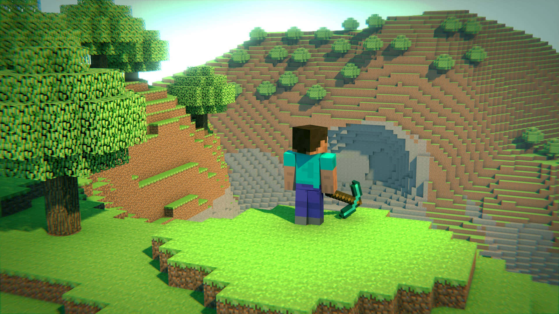 Minecraft Survival 桌布 壁紙 — 一位Minecraft玩家站在洞穴入口前，背景是塊狀像素風景，有綠樹和起伏的山丘，天空明亮。