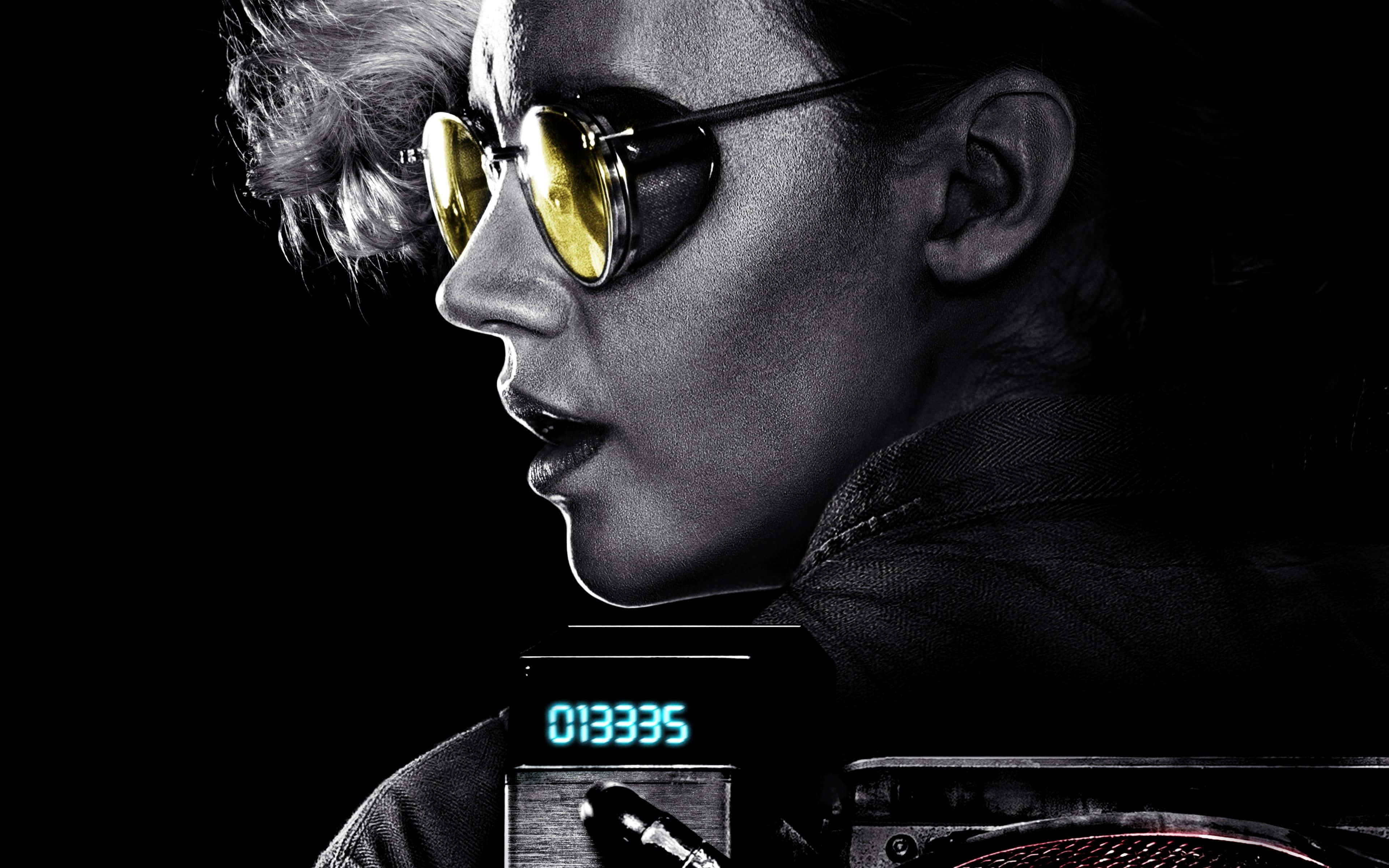 Ghostbusters 桌布 壁紙 — 一位側面女士戴著金色太陽眼鏡，背景為黑色，下方有發光的數碼顯示屏。