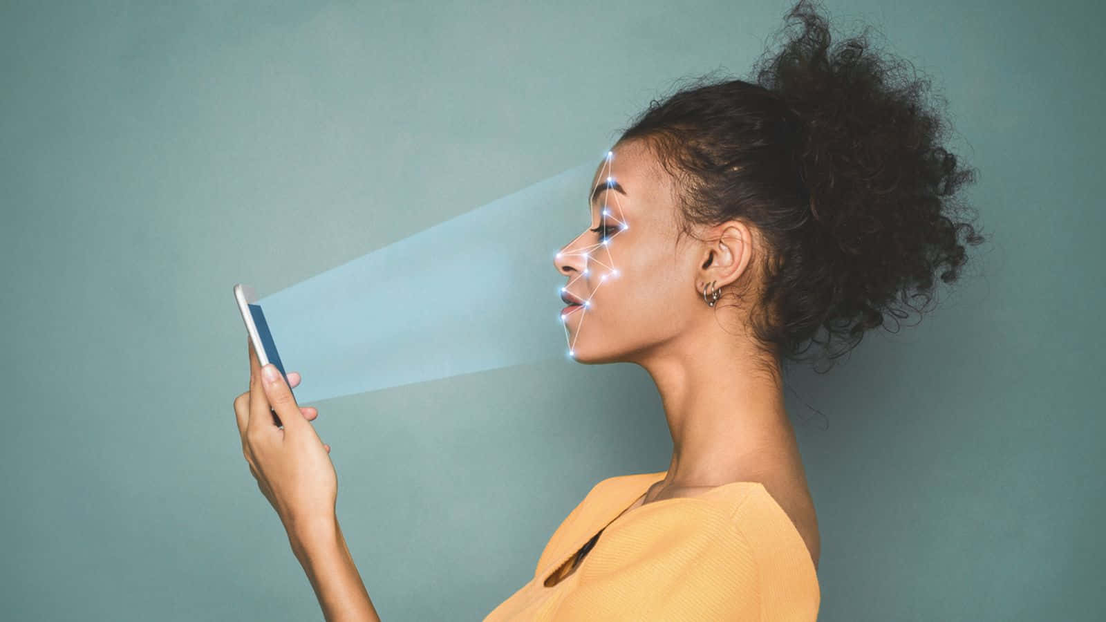 Face Recognition 桌布 壁紙 — 一位側面輪廓的女性手持電話，發光的藍色線條在未來感十足的擴增實境掃描中繪製她的臉部。