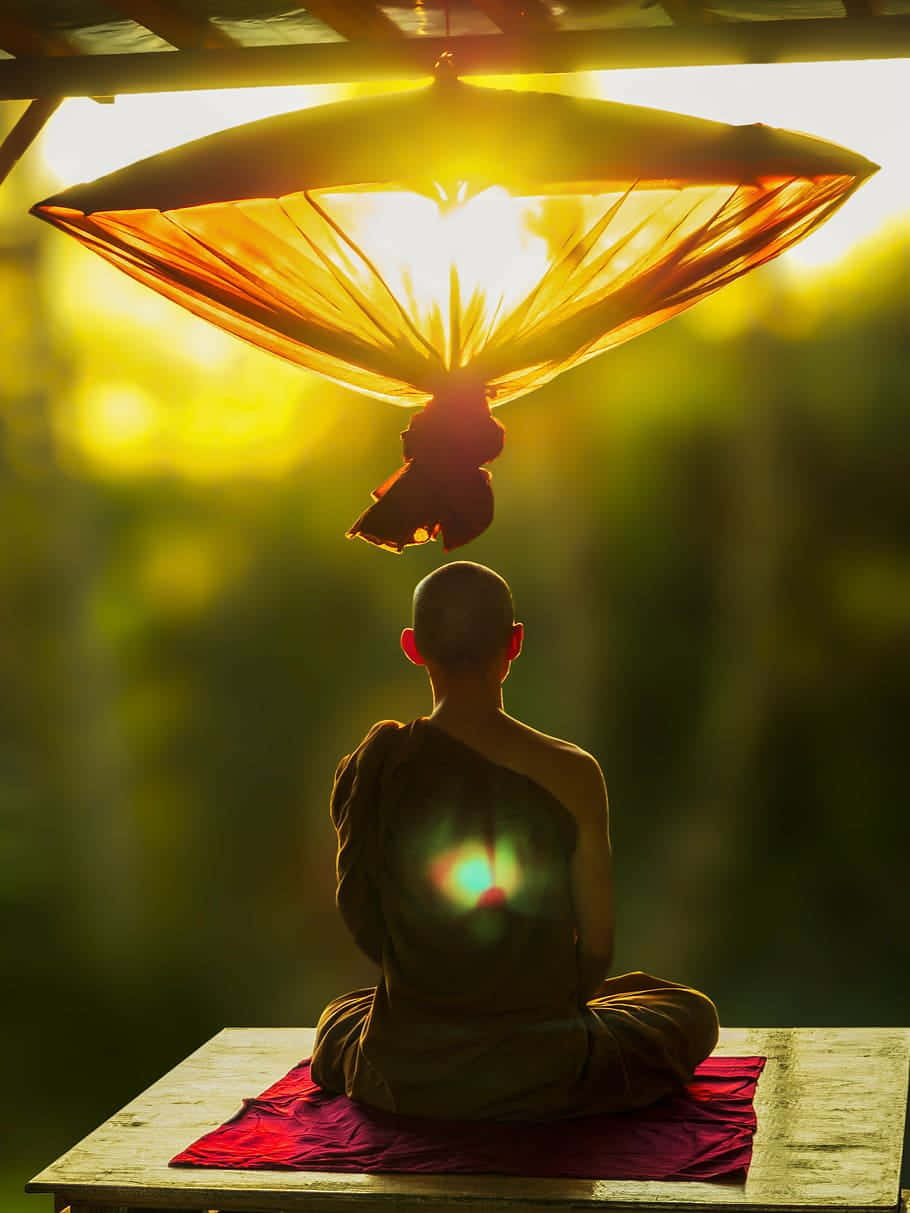 Concentration 桌布 壁紙 — 一位僧侶在發光的燈籠下打坐冥想，金色的陽光透過上方的布料灑落。