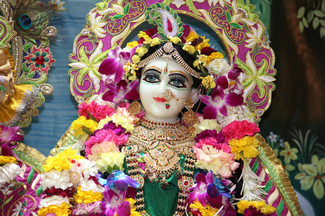 Hindu Temple 桌布 壁紙 — 一位光彩照人的神祇，飾以鮮豔的花朵和精緻的金飾，在色彩繽紛的華麗光環下。