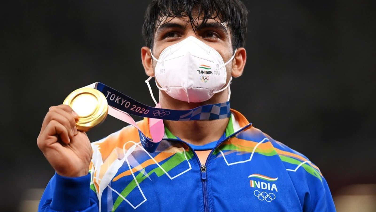 Neeraj Chopra 桌布 壁紙 — 一位印度奧運摔跤手在2020年東京奧運會期間自豪地舉著金牌，戴著Team India口罩。