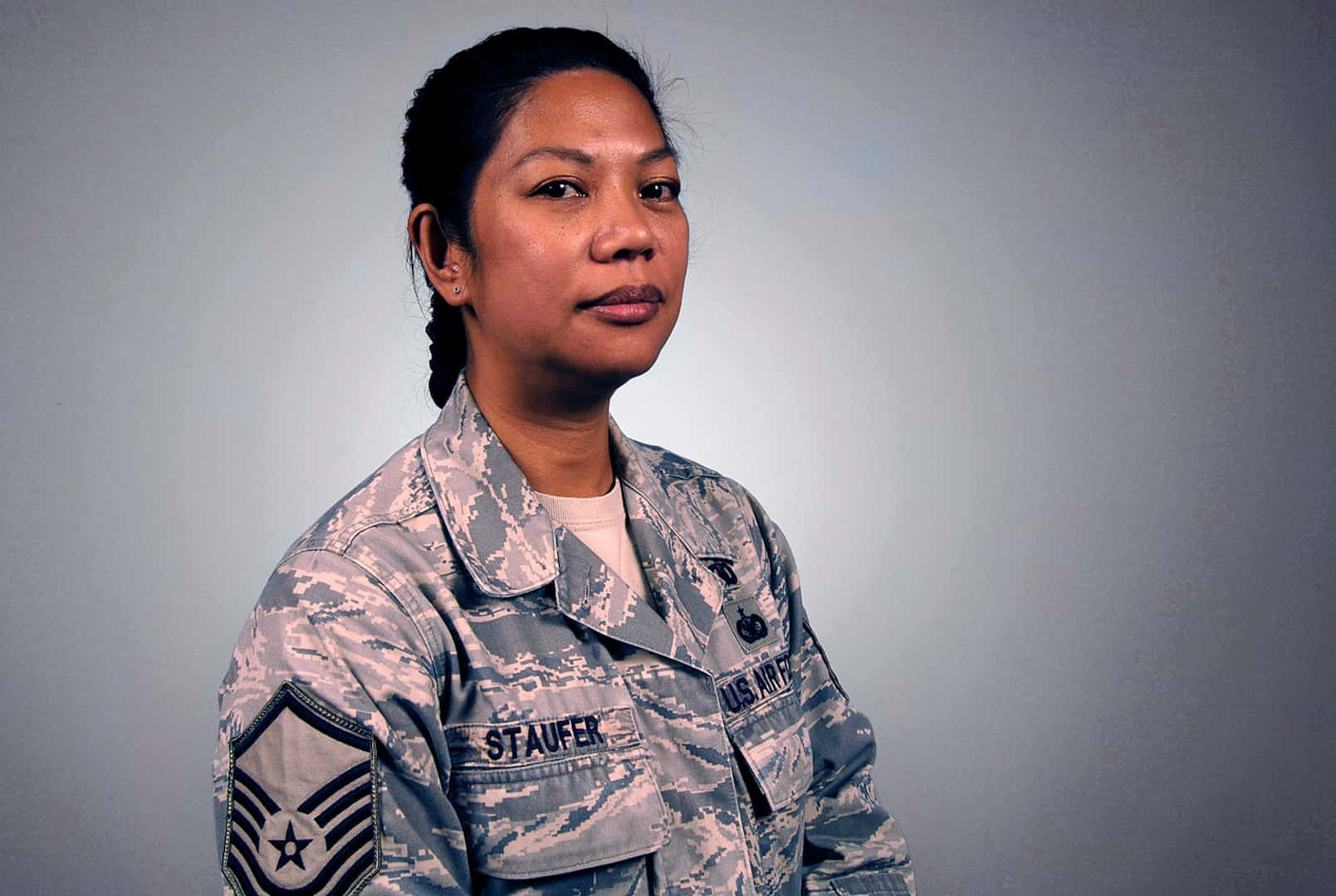 Air Force 桌布 壁紙 — 一位嚴肅嘅美國空軍女軍士身穿迷彩制服，喺純灰色攝影棚背景前擺姿勢。
