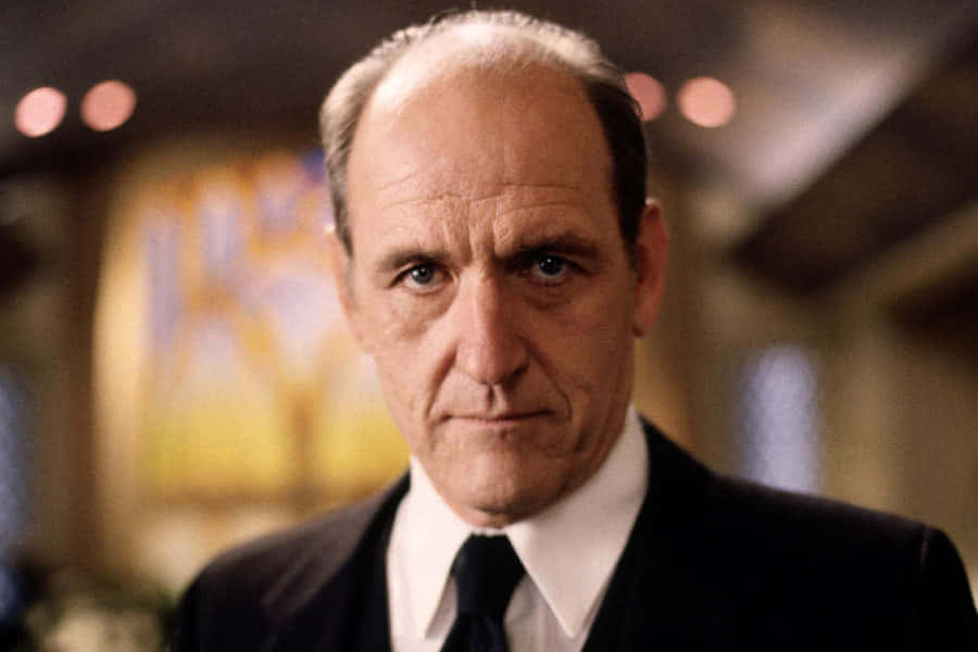 Richard Jenkins 桌布 壁紙 — 一位嚴肅的中年男子身穿深色西裝打領帶，一雙銳利的藍眼睛直視鏡頭的特寫。