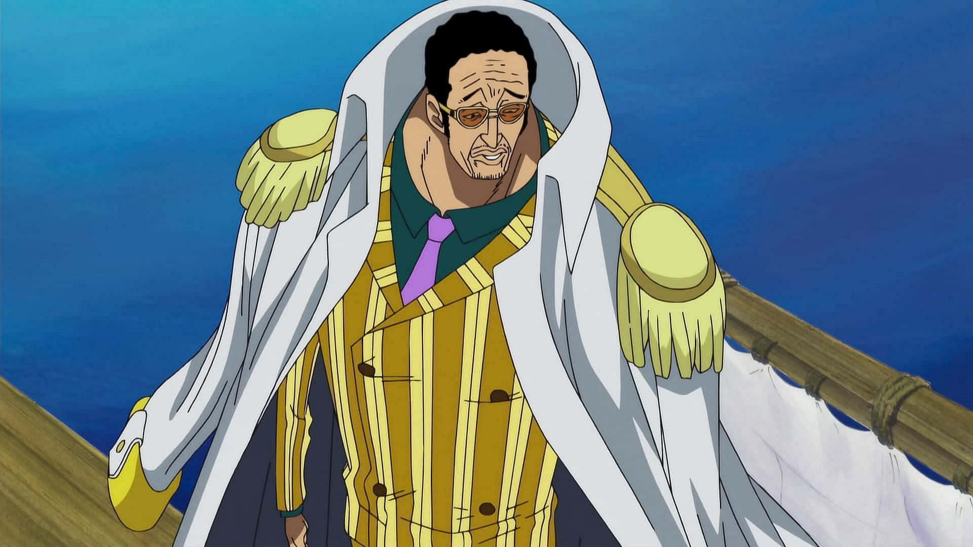 Kizaru 桌布 壁紙 — 一位嚴肅的動畫船長，身穿黃色條紋外套和白色披風，站在船甲板上，背景是廣闊的藍色海洋。