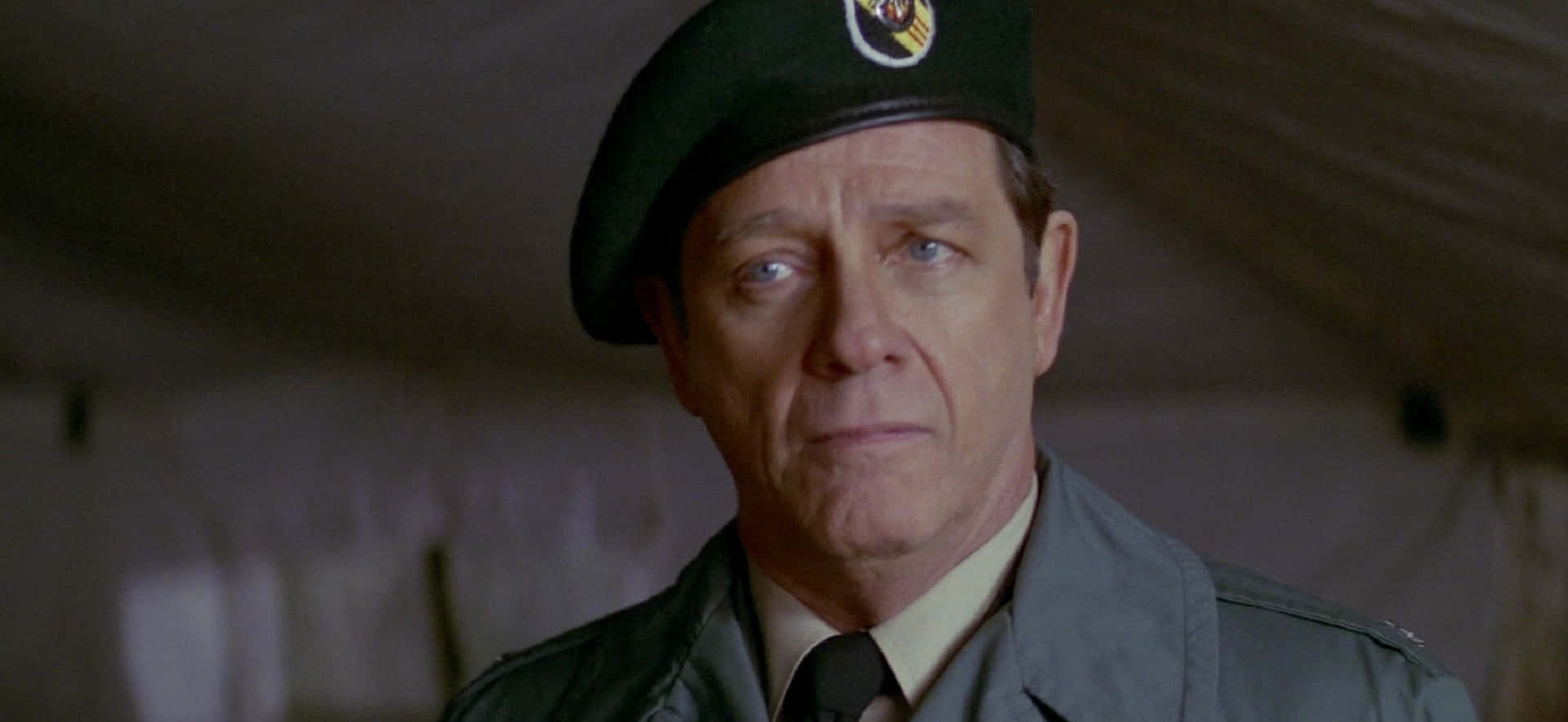 Richard Crenna 桌布 壁紙 — 一位嚴肅的軍官，身穿綠色貝雷帽和制服，在光線昏暗的帳篷內凝視著。