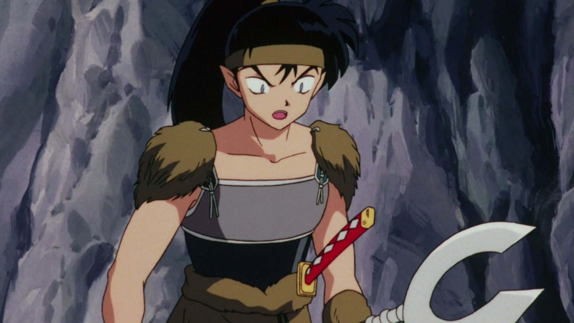 Inuyasha Koga 桌布 壁紙 — 一位堅定的動漫戰士，黑髮，身穿毛皮鑲邊盔甲，站在岩石洞穴中，手持大型武器。