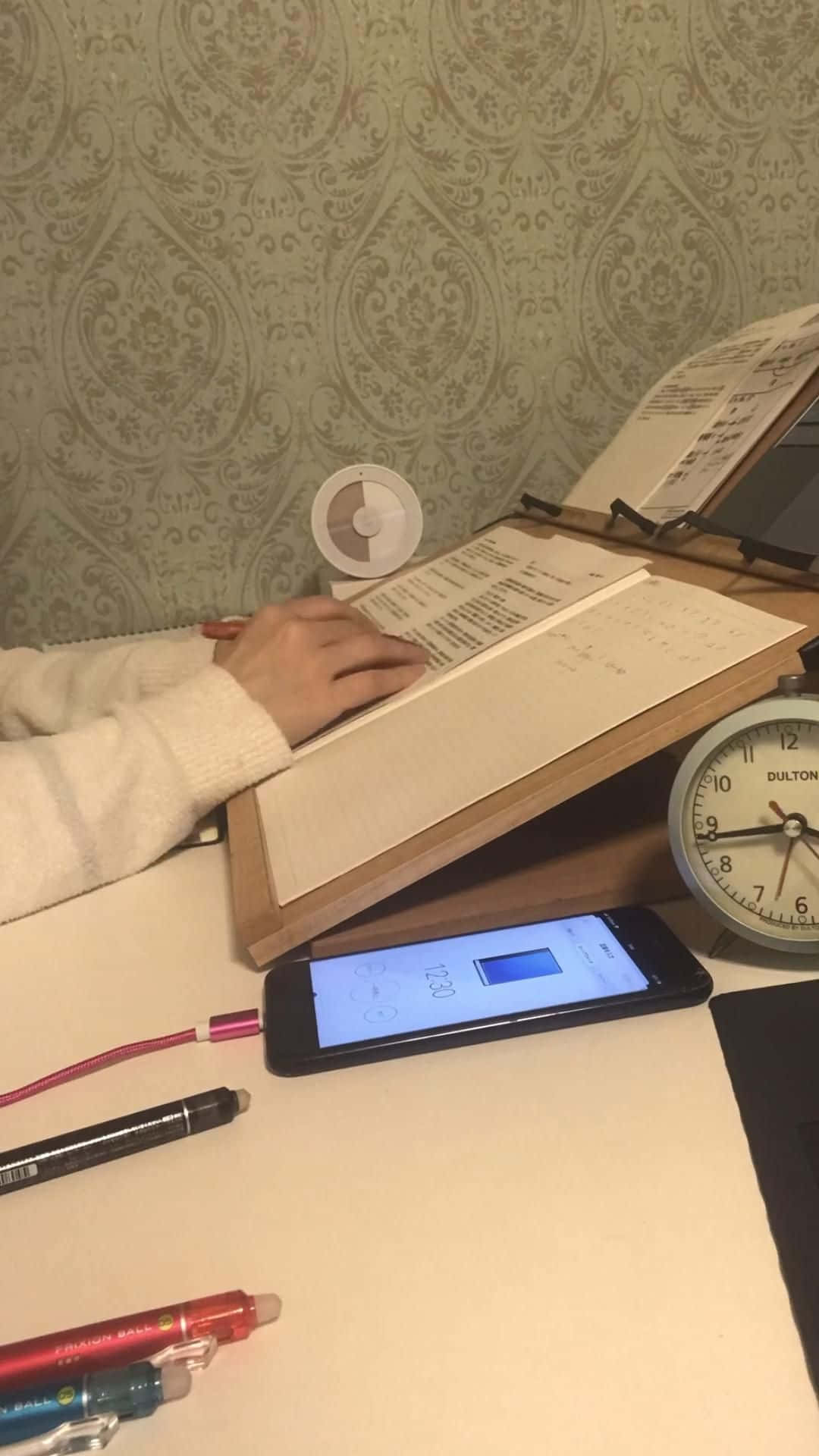 一位女士坐在辦公桌前，面前放著電話和筆記本 壁紙