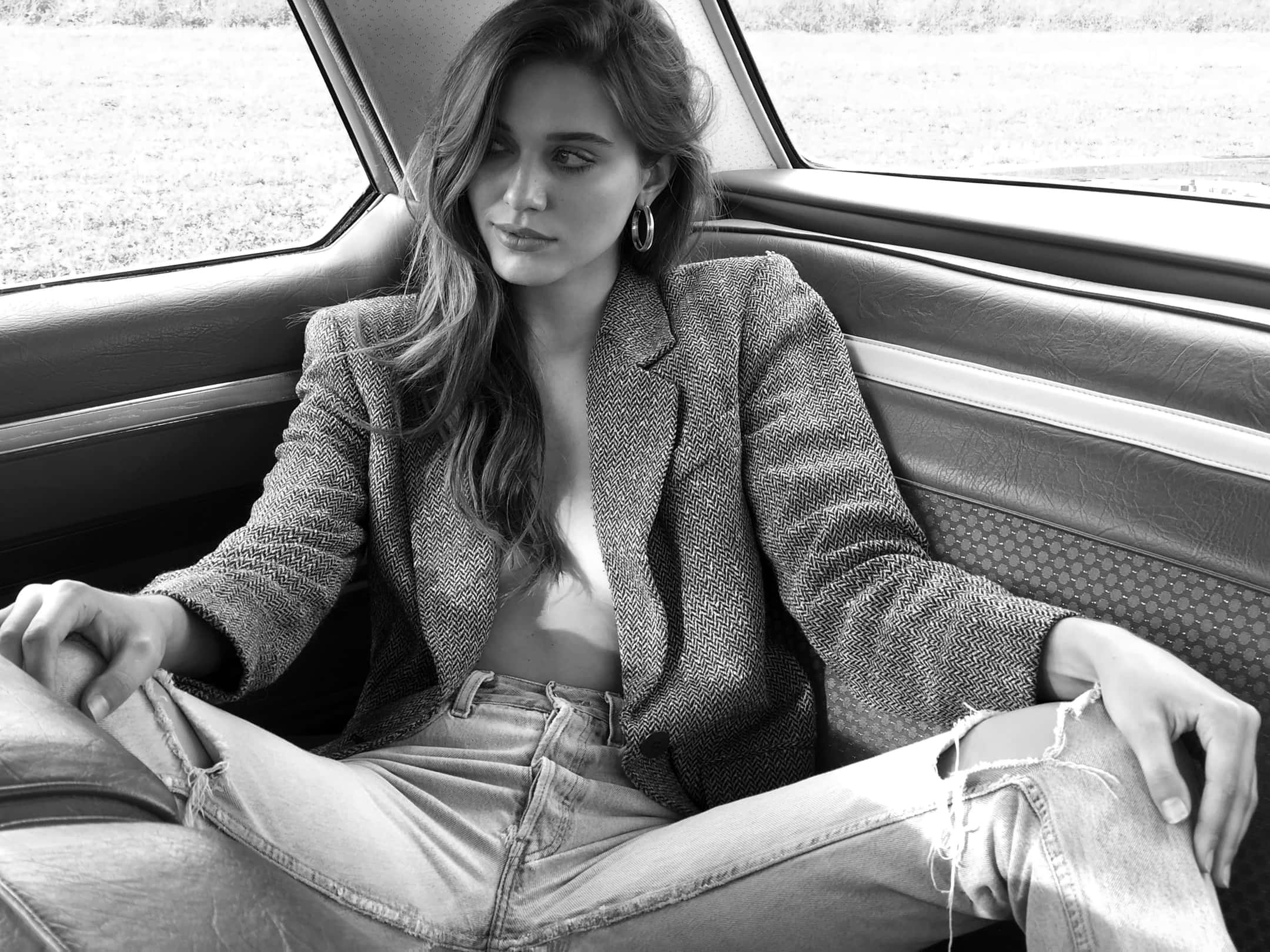 Black And White Fashion 桌布 壁紙 — 一位女士放鬆地坐在復古車內，透過窗戶沉思地向外凝望，以單色呈現。