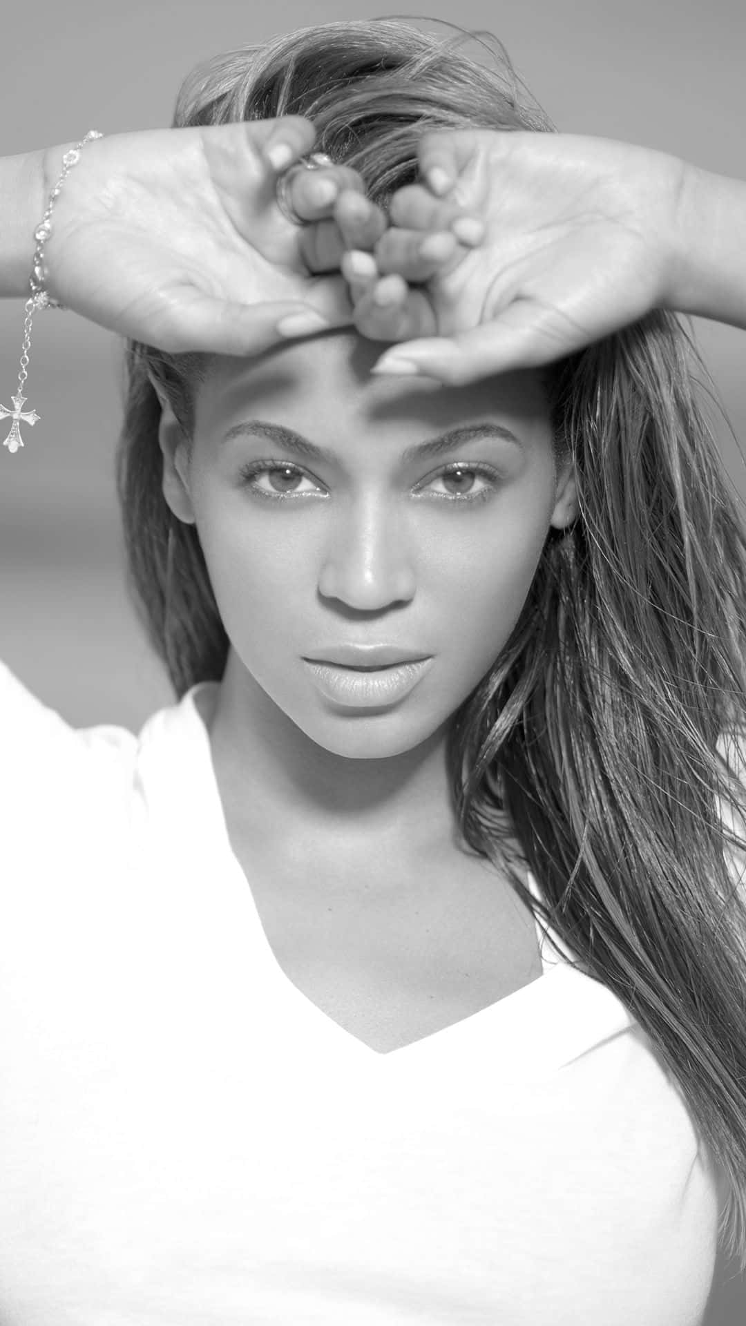 Beyoncé 桌布 壁紙 — 一位女士用手框住臉部的黑白肖像，戴著十字手鐲和白色上衣。