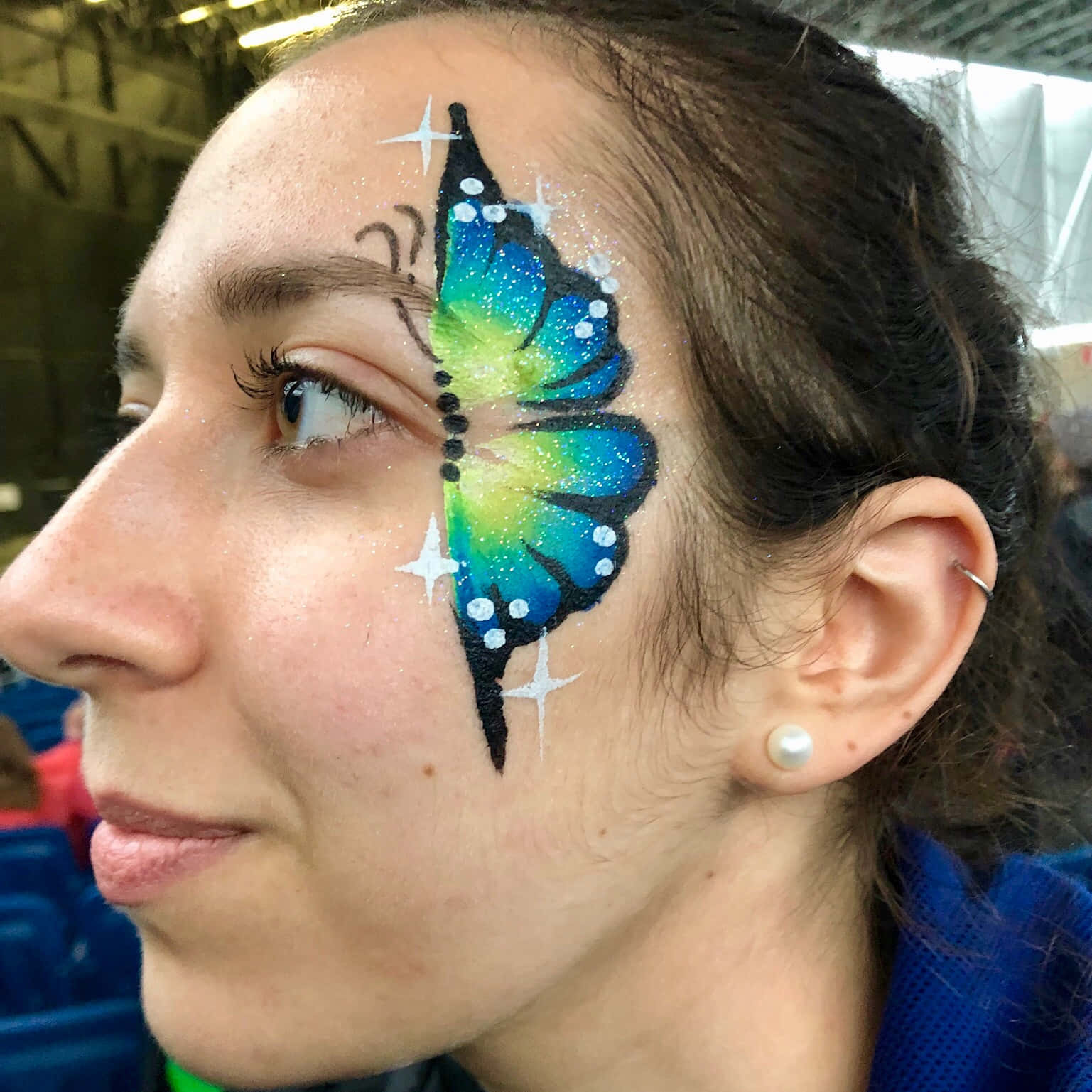 Butterfly Face Painting 桌布 壁紙 — 一位女士的臉龐，眼睛附近飾有充滿活力的藍色和綠色閃粉蝴蝶臉部彩繪設計。