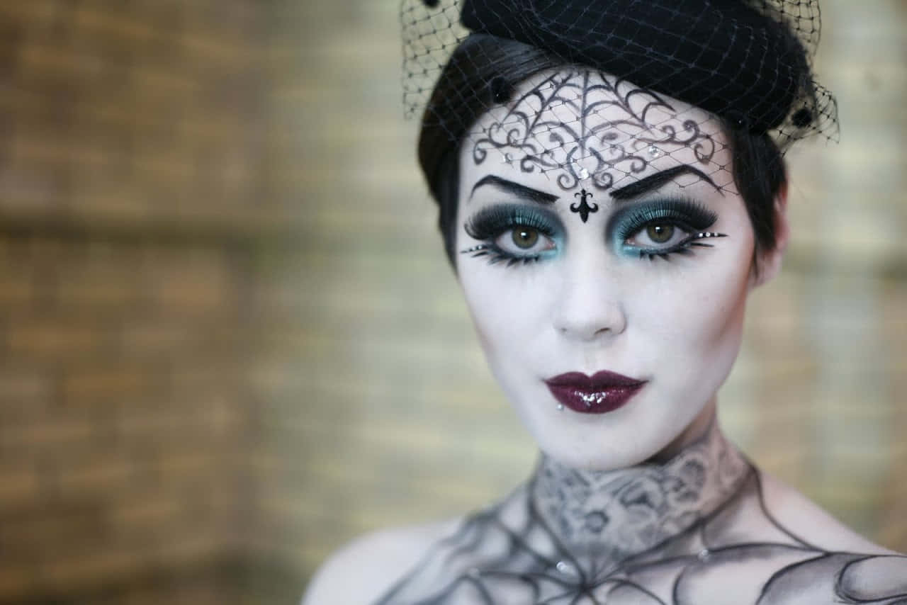 Halloween Face Paint 桌布 壁紙 — 一位女性，臉上帶有精緻的黑色蕾絲狀化妝和相配的面紗，在模糊的磚牆背景下強烈凝視。