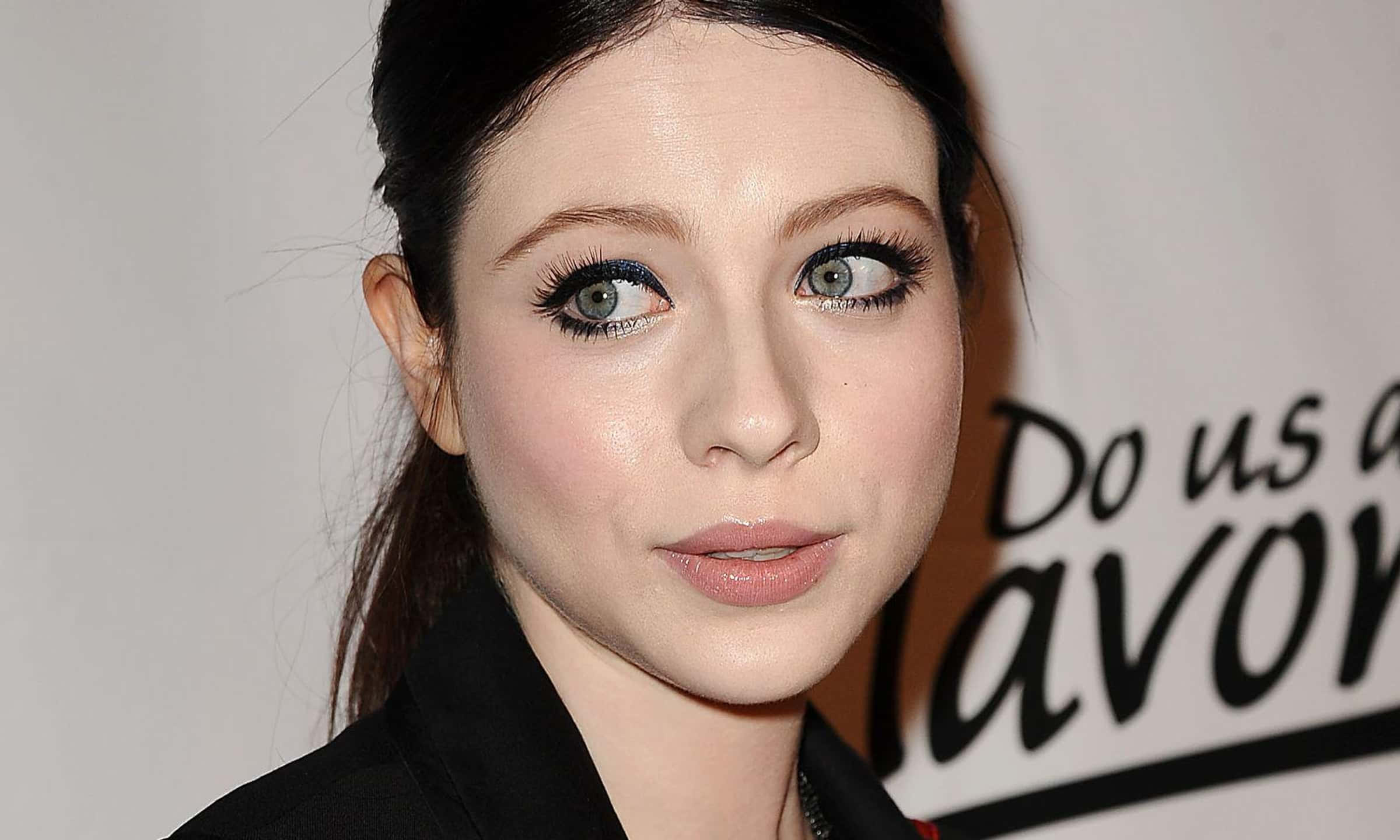 michelle trachtenberg 桌布 壁紙 — 一位女性嘅特寫肖像，佢有搶眼嘅藍色眼睛同大膽嘅眼線，背景係純白色。