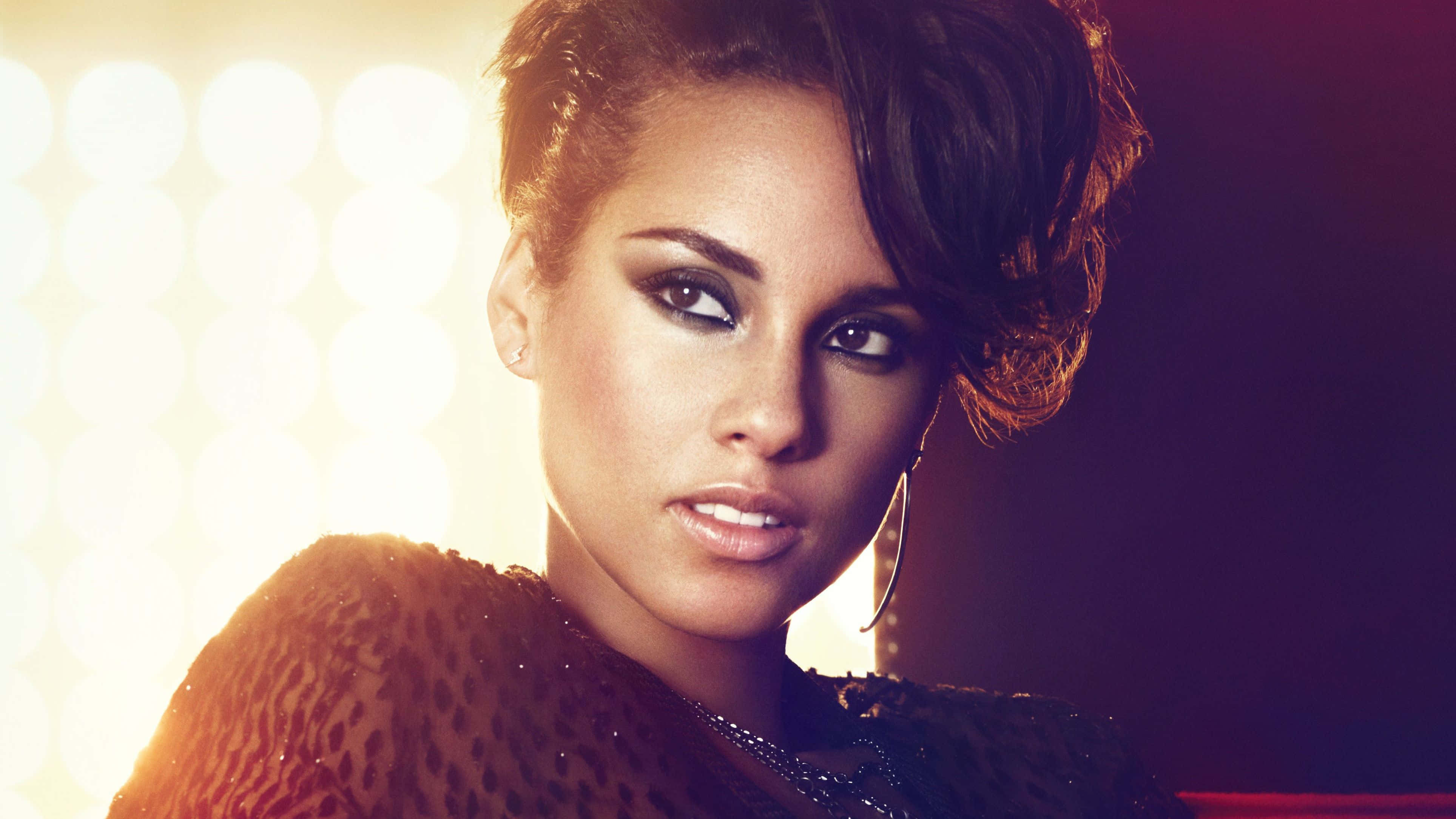 Alicia Keys 桌布 壁紙 — 一位妝容大膽、留著黑色短髮的迷人女性，在閃耀的攝影棚燈光背景下自信地凝視。