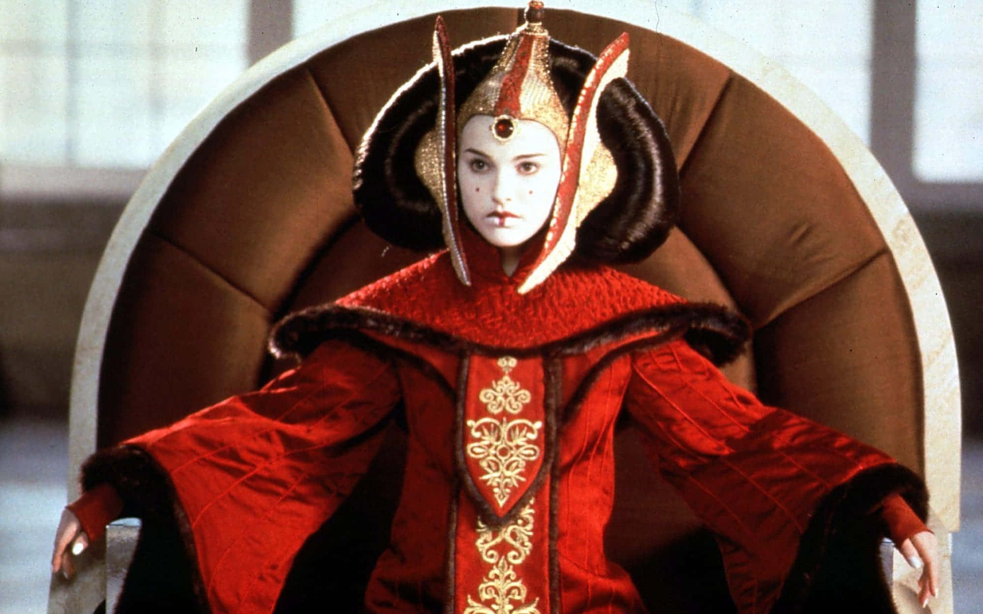 The Phantom Menace 桌布 壁紙 — 一位威嚴的外星女王，身穿華麗的紅色和金色禮服，端坐在彎曲的王座上，表情莊嚴。