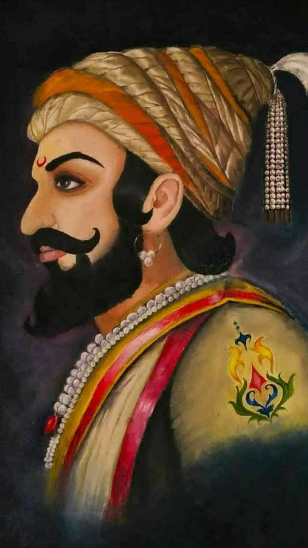 Indian 桌布 壁紙 — 一位威嚴的男子，留著黑色鬍鬚，戴著飾有珠子的華麗頭巾，在深色背景中側視。