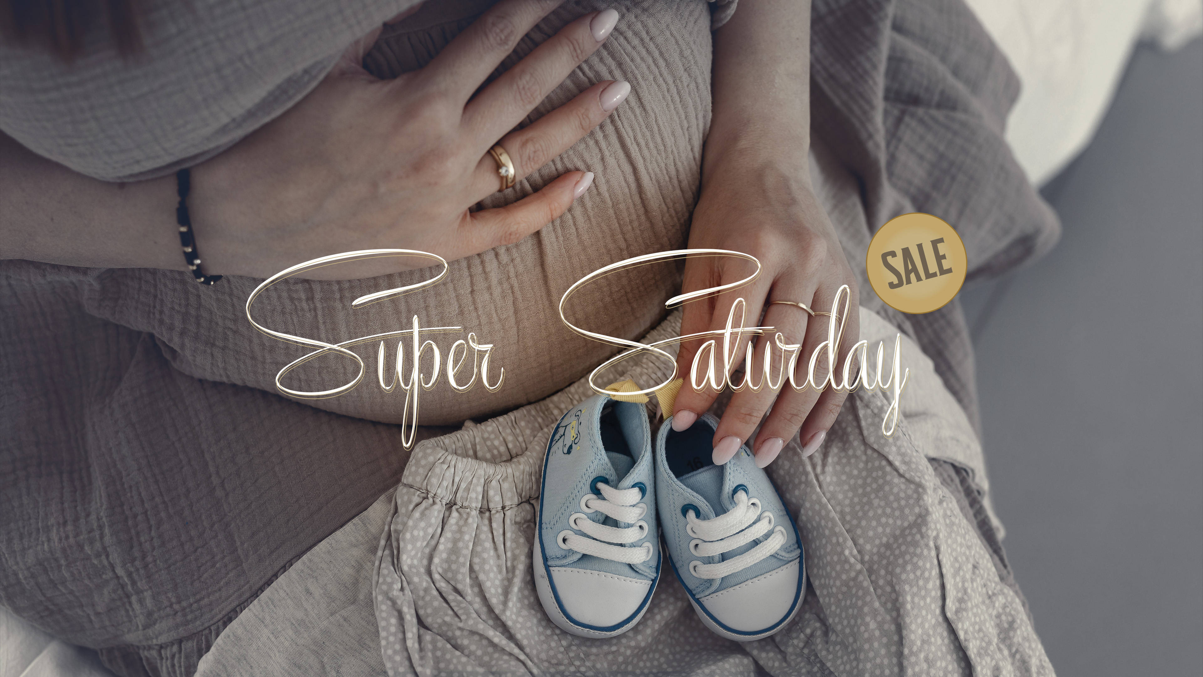 Pregnant 桌布 壁紙 — 一位孕婦用戴著戒指的雙手捧著腹部，旁邊放著嬰兒鞋，光線柔和暗淡。