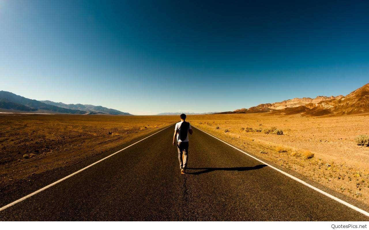 emo 桌布 壁紙 — 一位孤獨的旅行者在一望無際的清澈藍天下，沿著筆直的沙漠公路行走，兩旁是遠山。