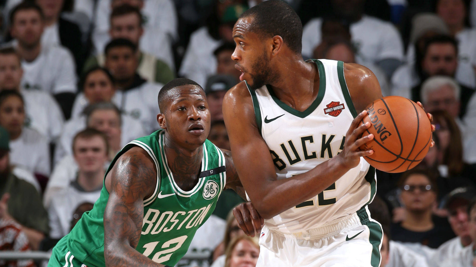 Khris Middleton Bucks 壁紙 — 一位密爾沃基公鹿球員在明亮的場館燈光下，於一場激烈的NBA比賽中突破波士頓塞爾特人防守球員。