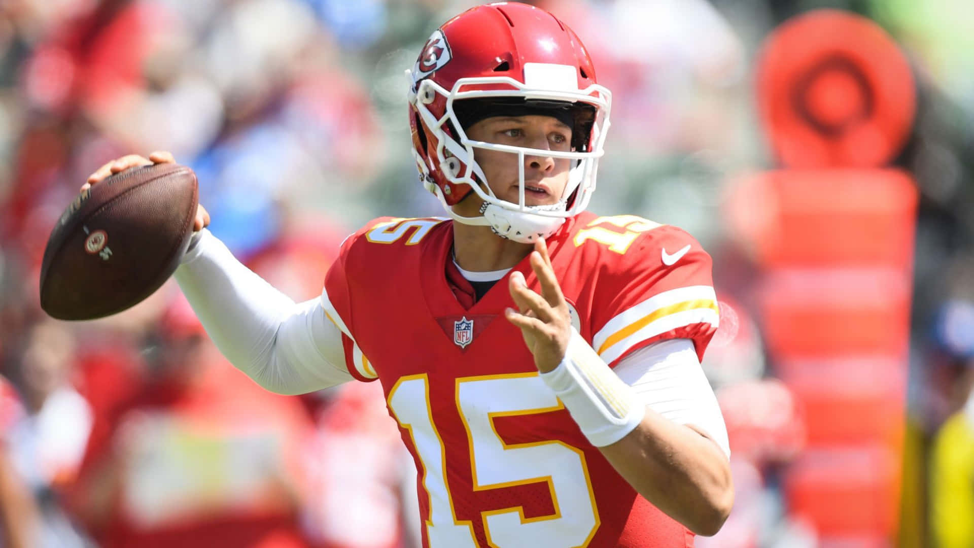 NFL四分衛身穿紅色球衣在日間比賽中擲出橄欖球。 — 帕特里克·馬霍姆斯 壁紙
