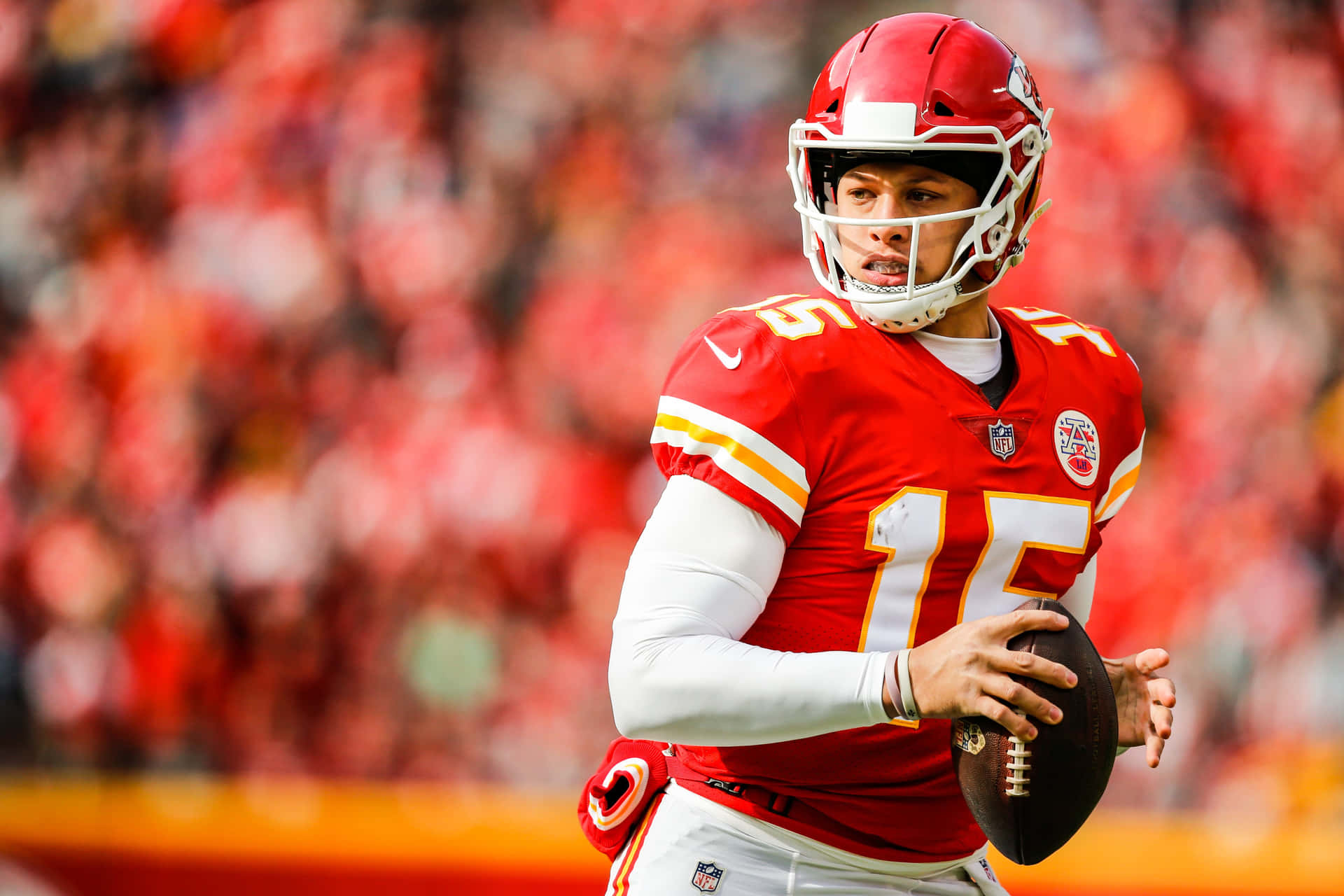 NFL四分衛身穿紅色球衣在比賽中手持橄欖球。 — 帕特里克·馬霍姆斯 壁紙