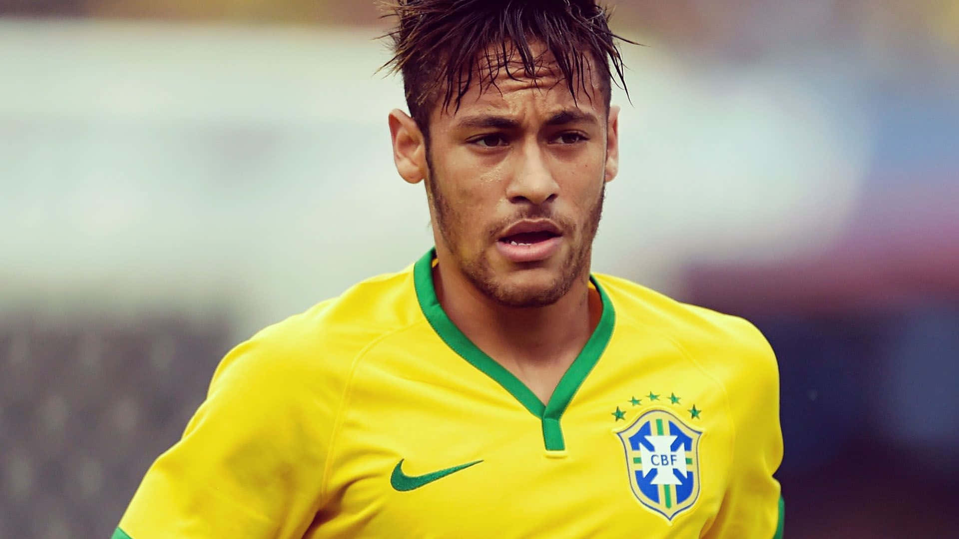 Neymar 桌布 壁紙 — 一位專注的巴西足球員，身穿鮮黃色球衣，帶有綠色點綴和CBF徽章，在比賽中專注地向前看。