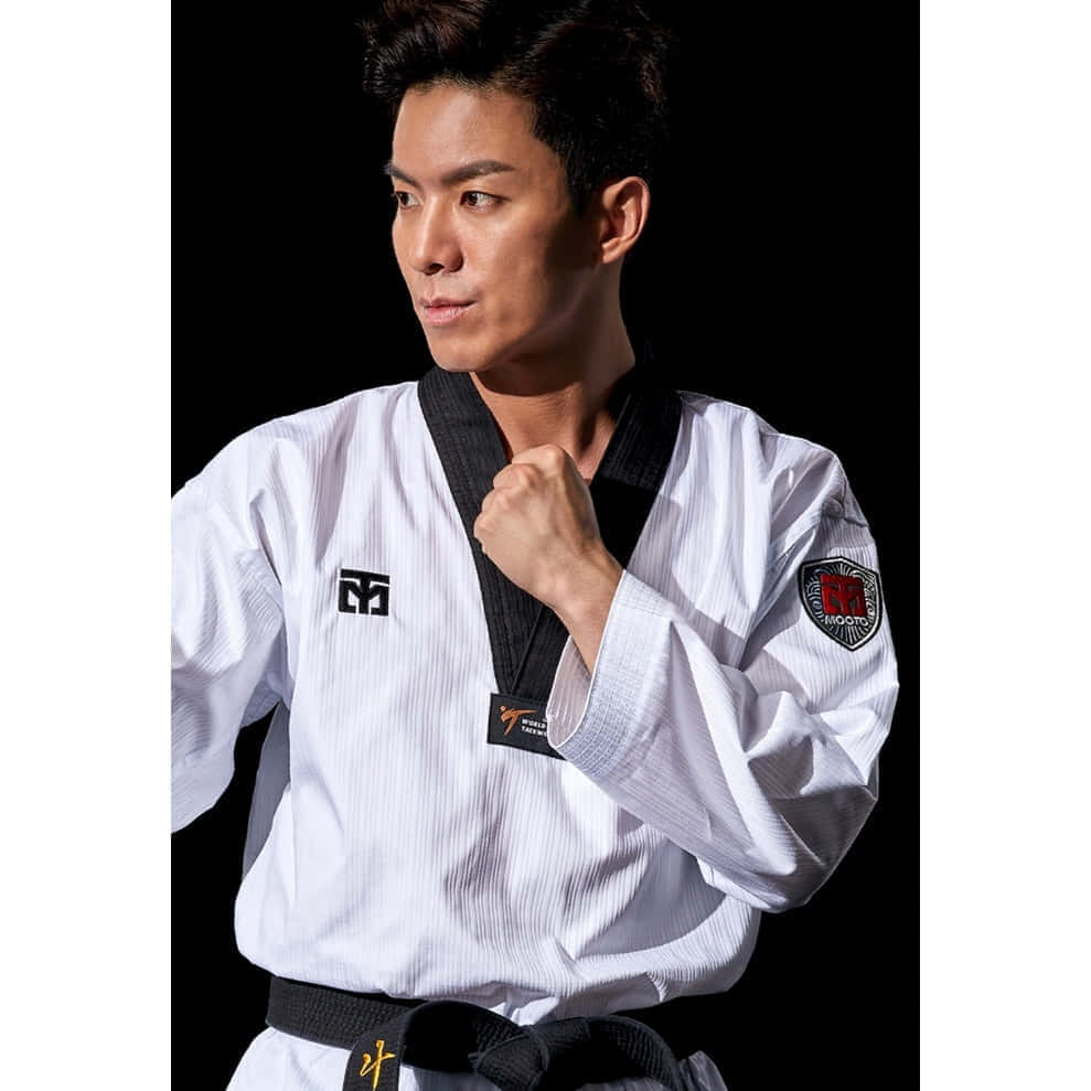 Martial Arts Uniforms 桌布 壁紙 — 一位專注的武術家身穿白色道服，繫著黑帶，在純黑背景前自信地擺出姿勢。