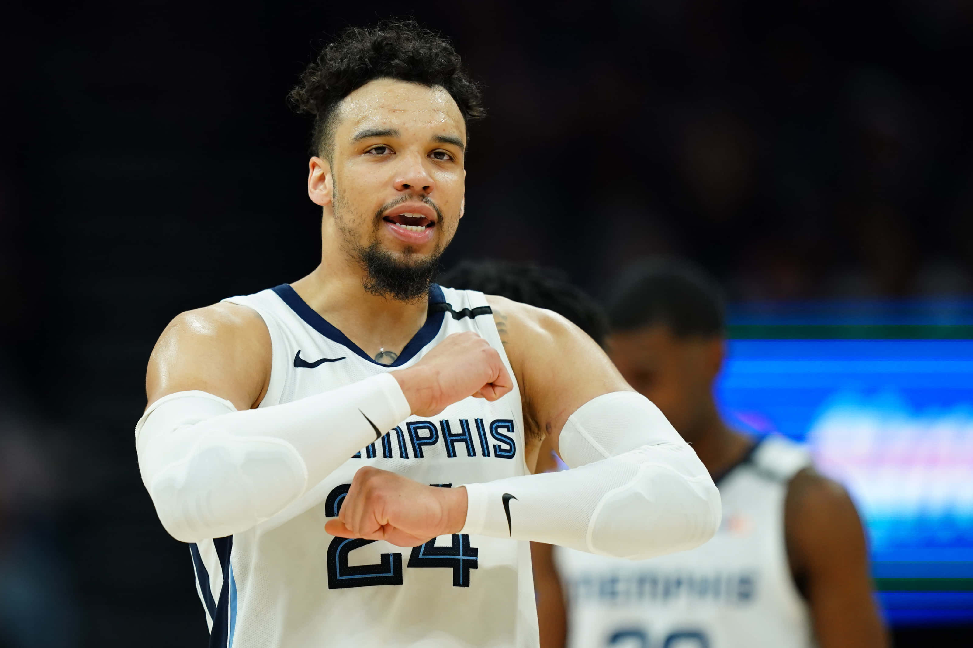 Dillon Brooks 桌布 壁紙 — 一位專注的籃球運動員身穿白色孟菲斯球衣（24號），在明亮的場館燈光下比賽時彎曲雙臂。