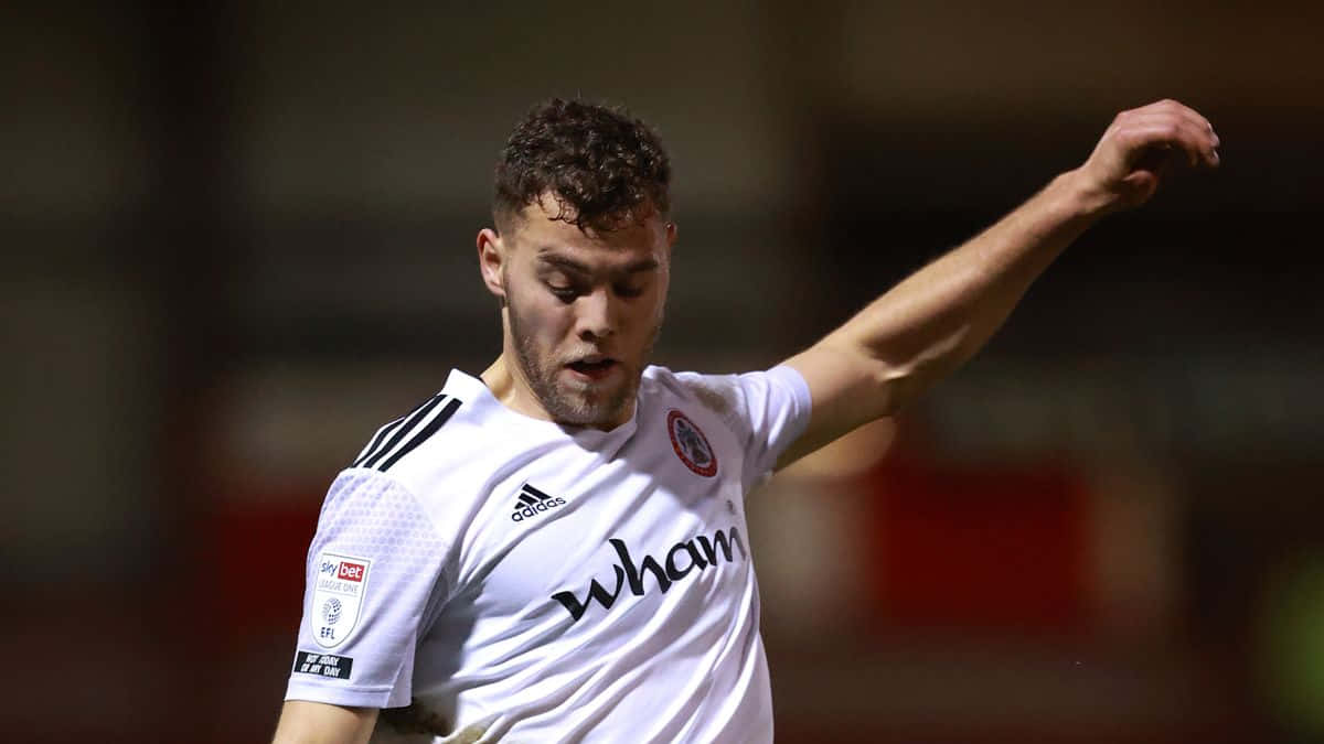 Bolton Wanderers Fc 桌布 壁紙 — 一位專注的足球員身穿印有 'wham' 品牌的白色球衣，在球場燈光下準備踢球。