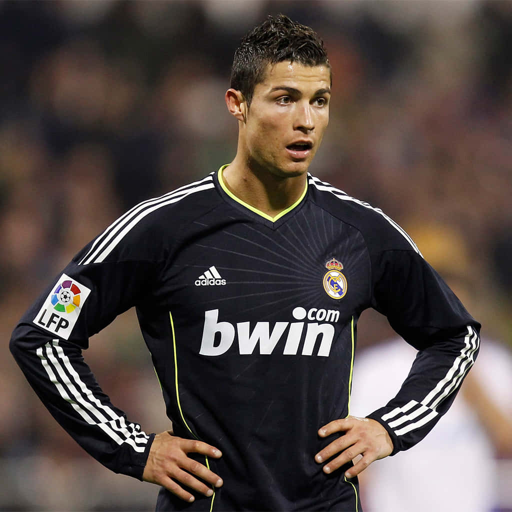 Ronaldo 桌布 壁紙 — 一位專注的足球員身穿黑色皇家馬德里球衣，在夜間比賽中於球場燈光下雙手叉腰站立。