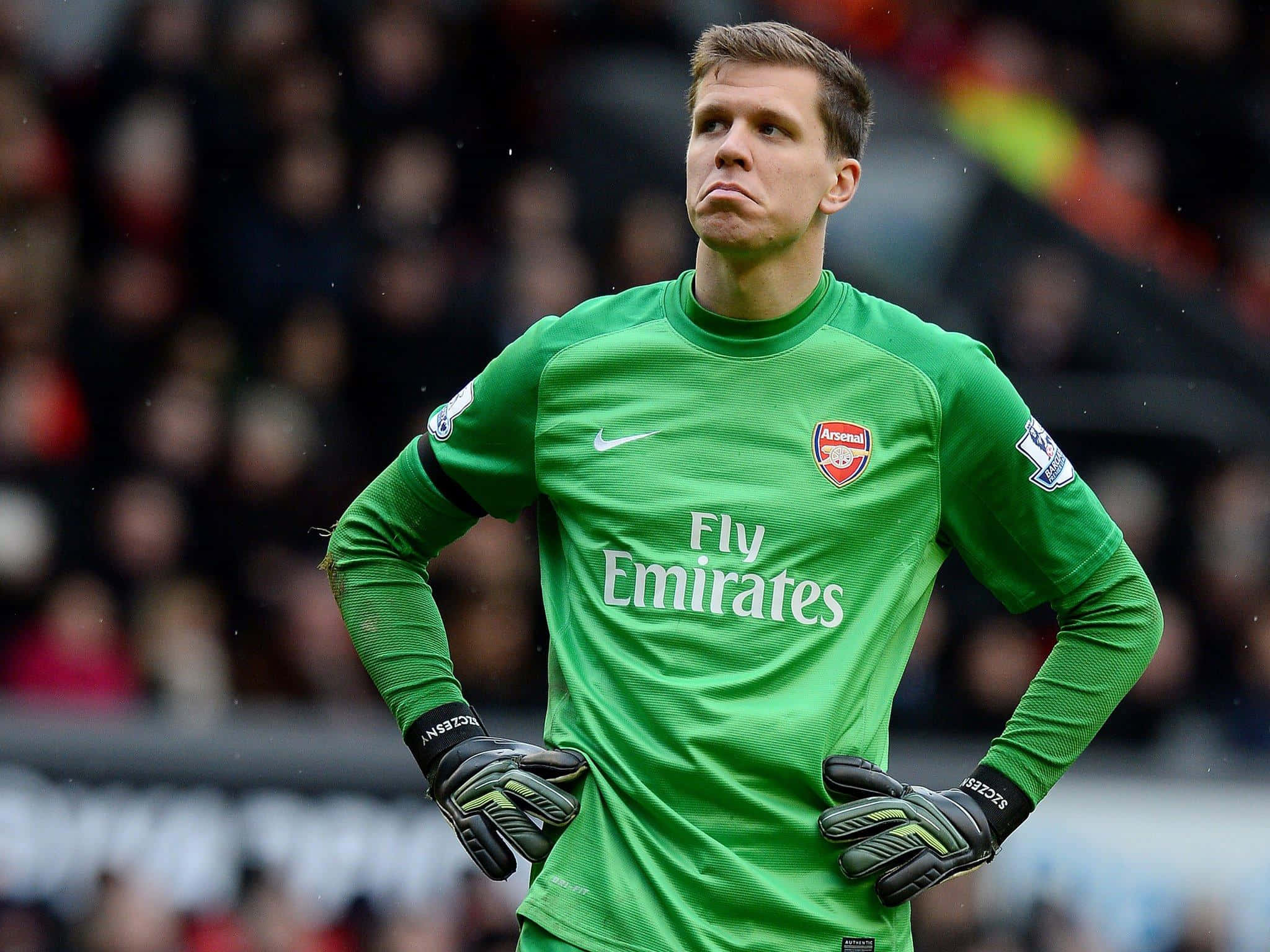 Wojciech Szczesny 桌布 壁紙 — 一位專注的足球守門員穿著亮綠色阿仙奴球衣，在比賽中雙手叉腰站立。