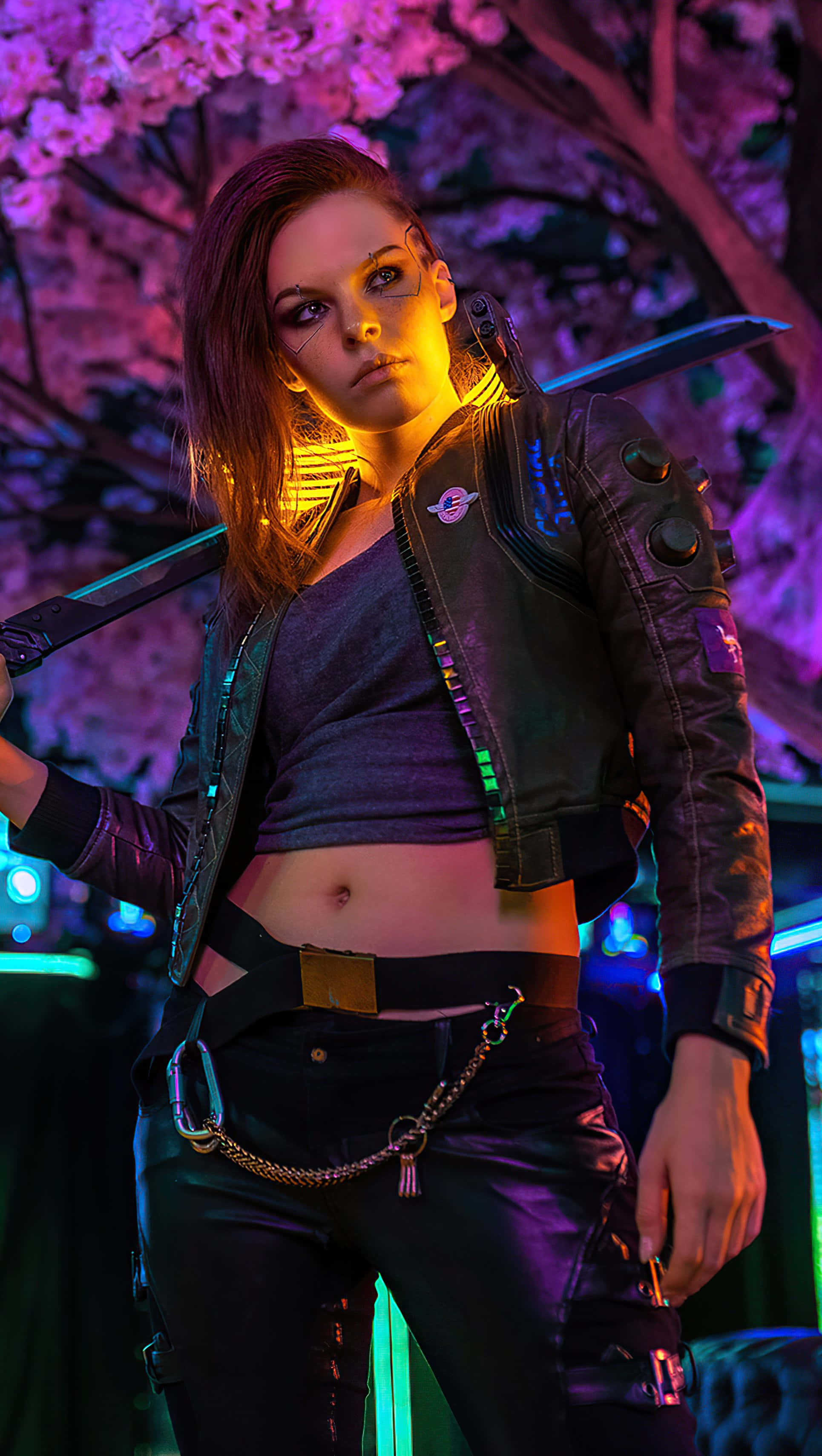 Cyberpunk 2077 Characters 桌布 壁紙 — 一位帶有發光裝飾的賽博龐克女性，站在霓虹燈下的櫻花樹旁，手持一把劍。
