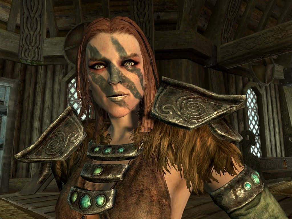Aela The Huntress 桌布 壁紙 — 一位帶有部落臉部彩繪和華麗盔甲的兇猛女戰士，站在質樸的木製大廳中。