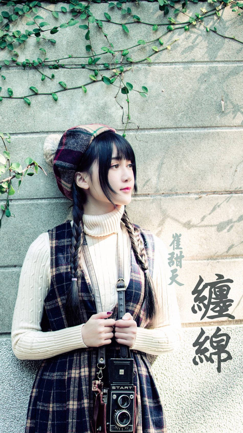 女孩 桌布 壁紙 — 一位年輕女子，辮子頭髮，戴著格子帽，靠著爬滿藤蔓的石牆，手持復古相機。