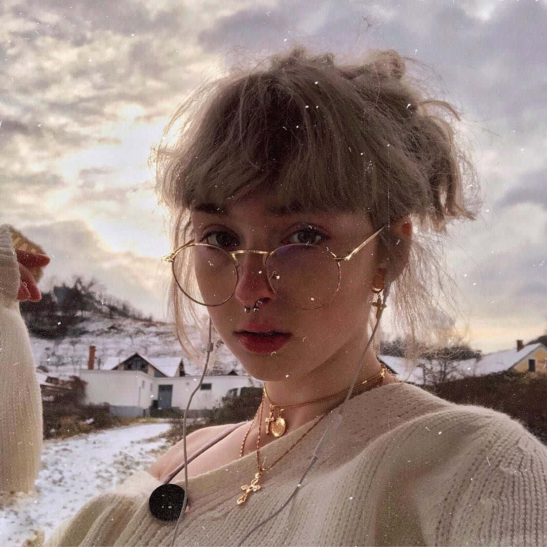 戴眼鏡和針織毛衣的年輕女性，在黃昏時分的雪村戶外。