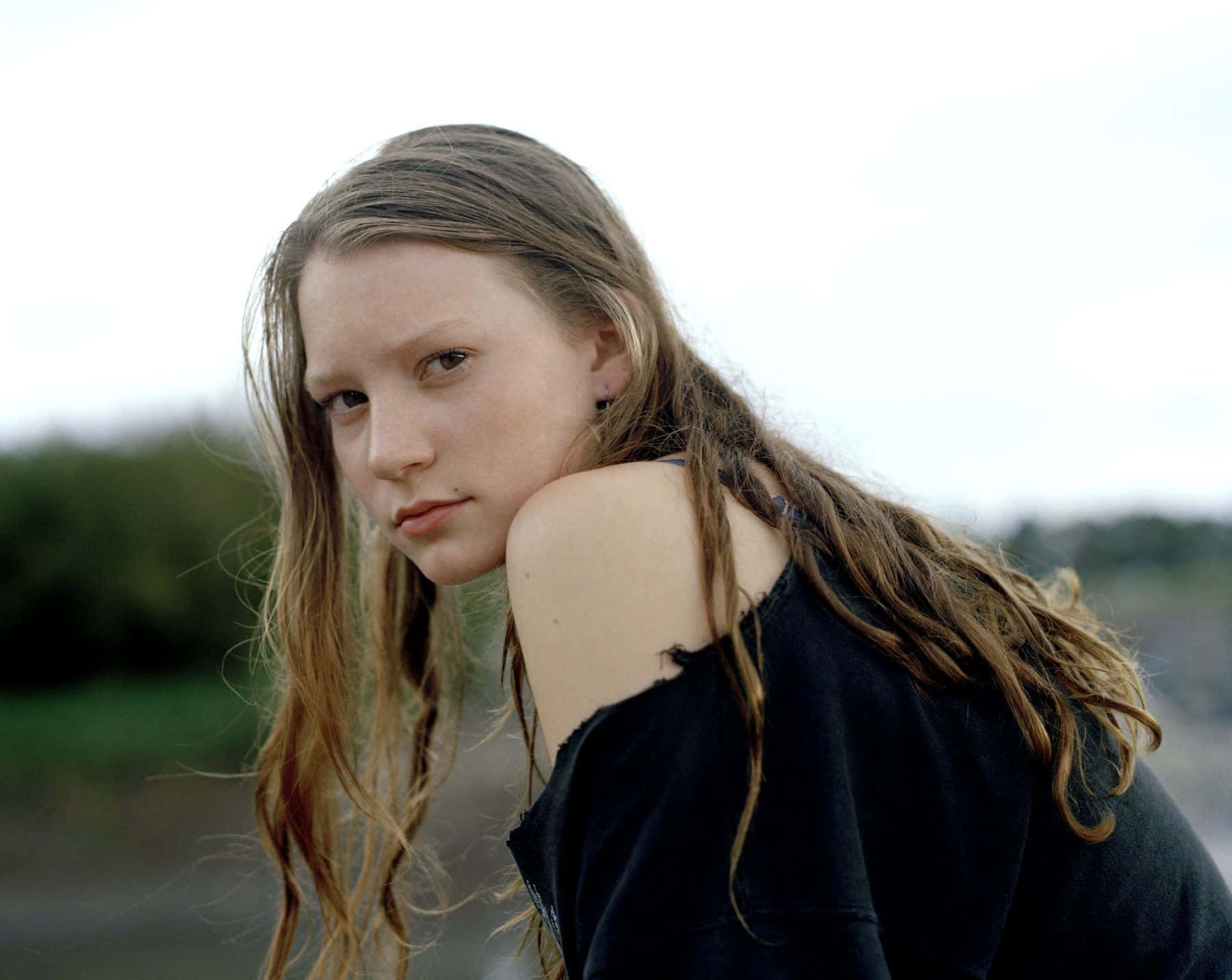 Mia Wasikowska 桌布 壁紙 — 一位年輕女子濕著頭髮，在柔和模糊的戶外背景下直視鏡頭。