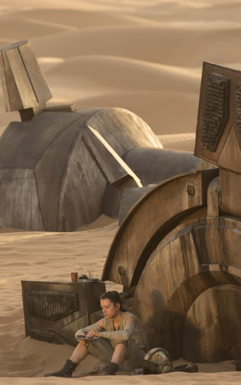 Jakku 桌布 壁紙 — 一位年輕女子獨自坐在廣闊的沙漠中，旁邊是一艘巨大的失事太空船，沐浴在溫暖的金色光芒中。