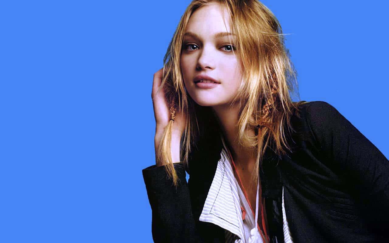 Gemma Ward 桌布 壁紙 — 一位年輕女性，一頭凌亂的金髮，在純淨鮮豔的藍色背景前溫柔凝視。