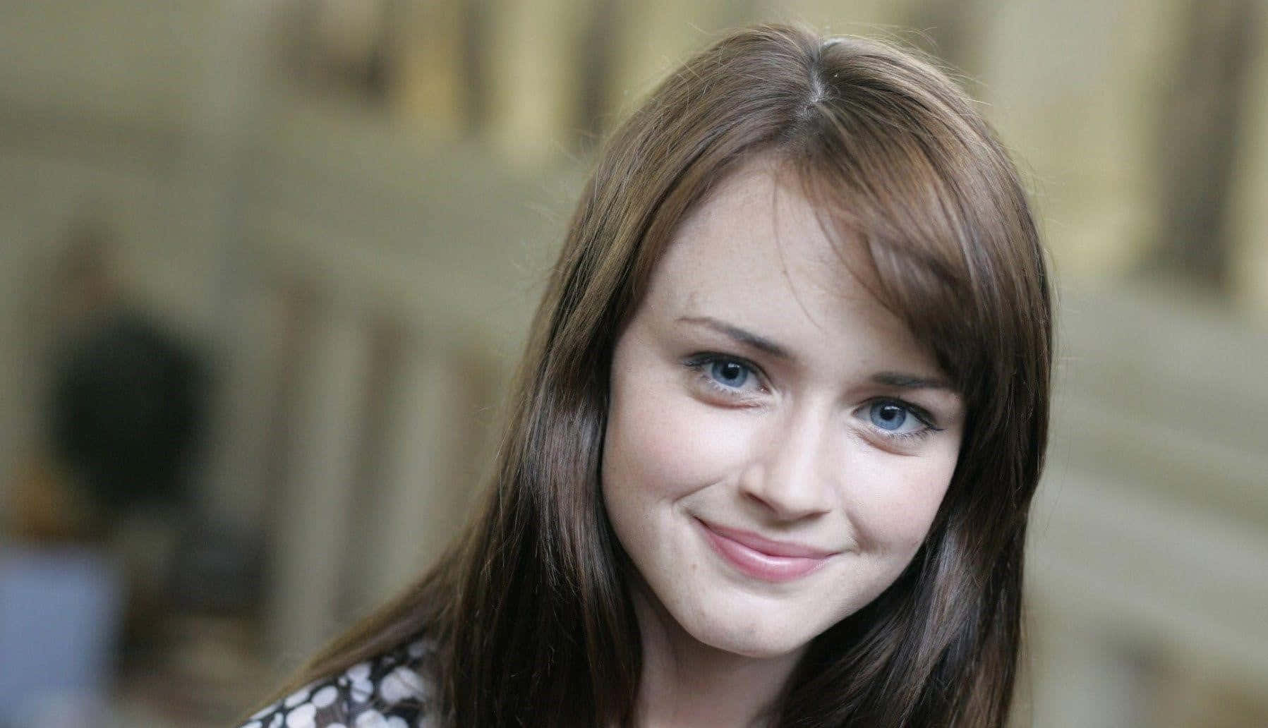 Alexis Bledel 桌布 壁紙 — 一位年輕女性嘅特寫肖像，佢有棕色頭髮同藍色眼睛，正溫暖咁向鏡頭微笑。