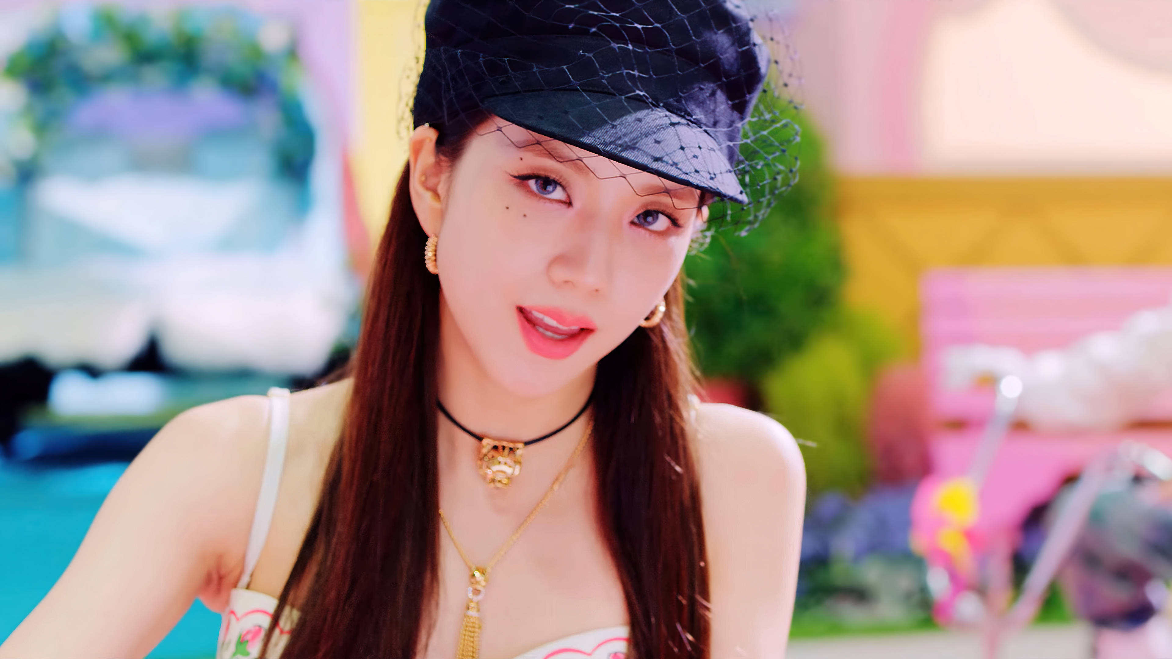 BLACKPINK Jisoo Ice Cream 壁紙 — 一位年輕女性留著長長的棕色頭髮，戴著黑色網帽和金飾，在色彩繽紛的戶外環境中對著鏡頭微笑。
