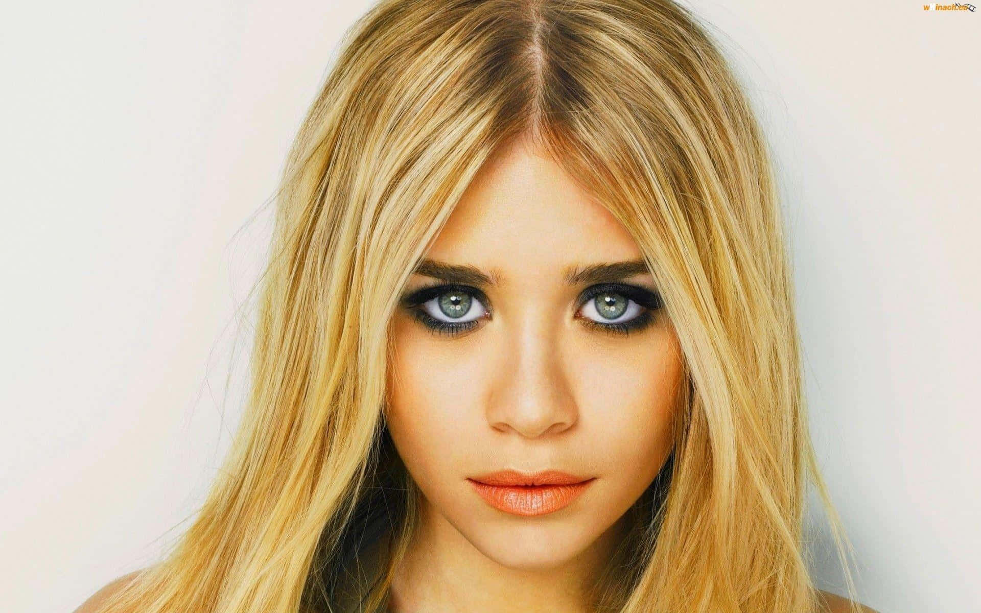 Mary Kate Olsen 桌布 壁紙 — 一位年輕女性的特寫肖像，擁有引人注目的藍色眼睛和長長的金色頭髮，背景為純白色。