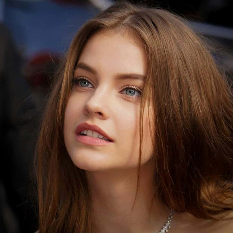 Beautiful Woman 桌布 壁紙 — 一位年輕女性的特寫肖像，擁有引人注目的藍色眼睛和棕色頭髮，以柔和的表情向上凝視。