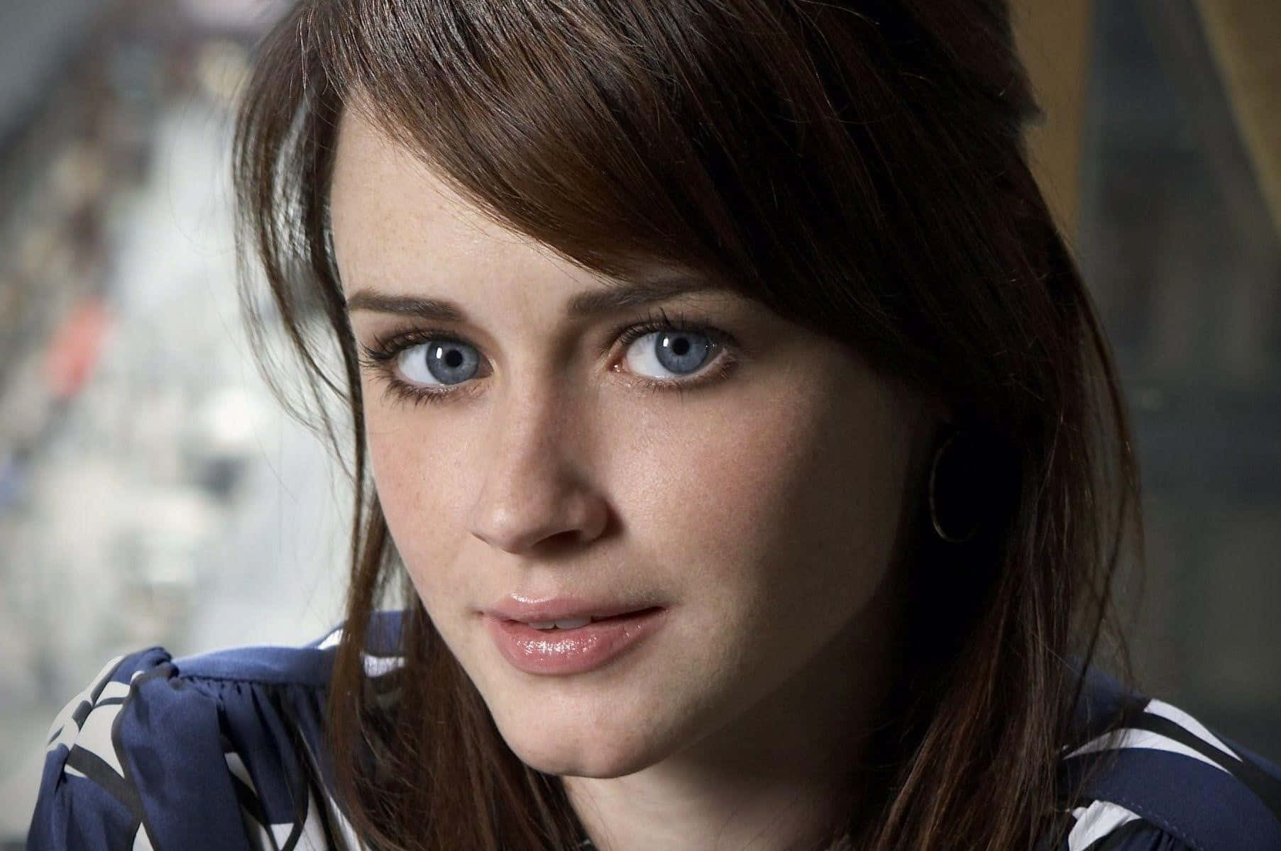Alexis Bledel 桌布 壁紙 — 一位年輕女性的特寫肖像，擁有引人注目的藍色眼睛和棕色頭髮，直視鏡頭。