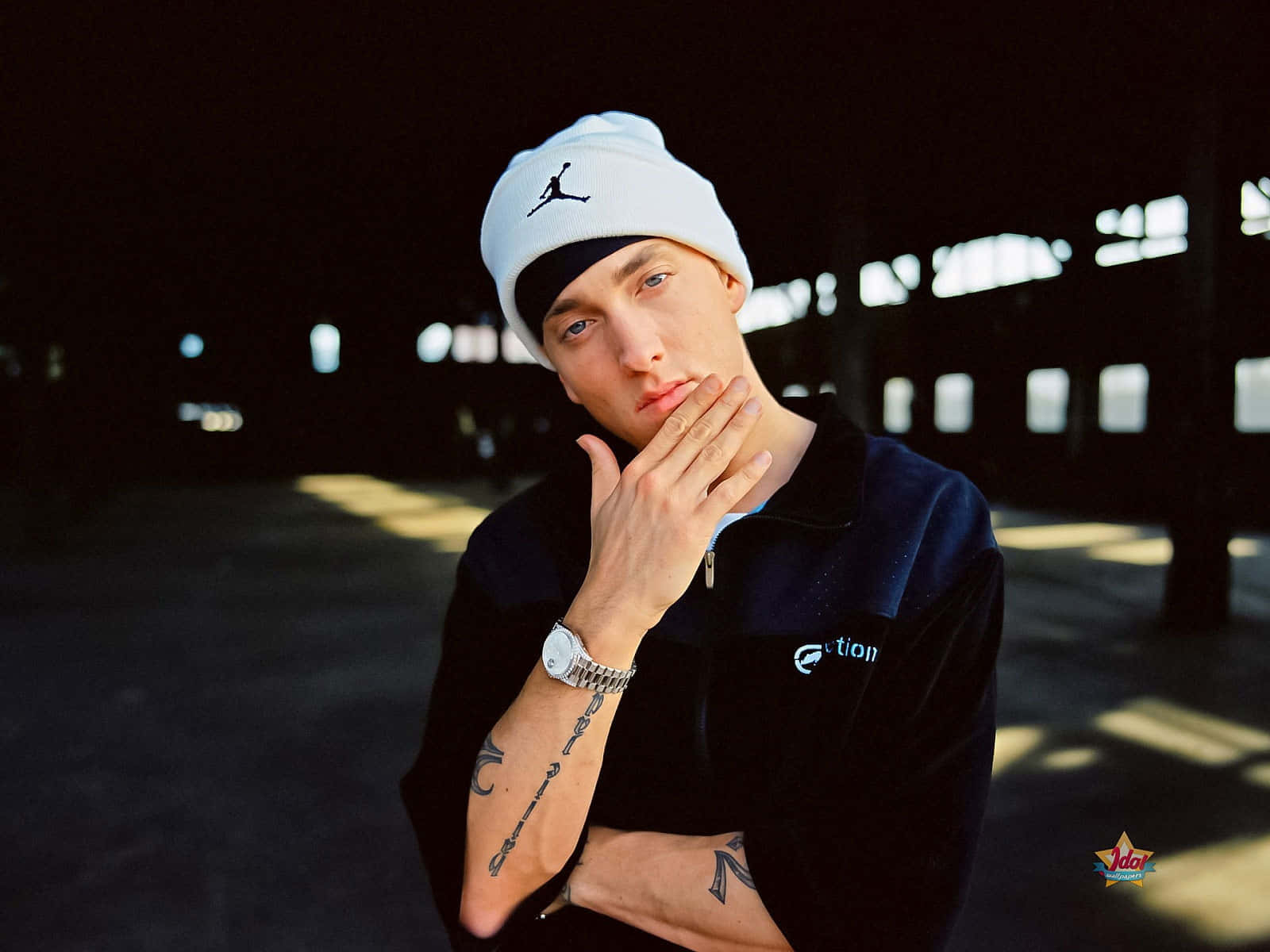 Eminem 桌布 壁紙 — 一位年輕男子戴著白色Jordan冷帽和深色外套，在夜晚戲劇性的燈光下，手靠近臉部沉思擺姿勢。