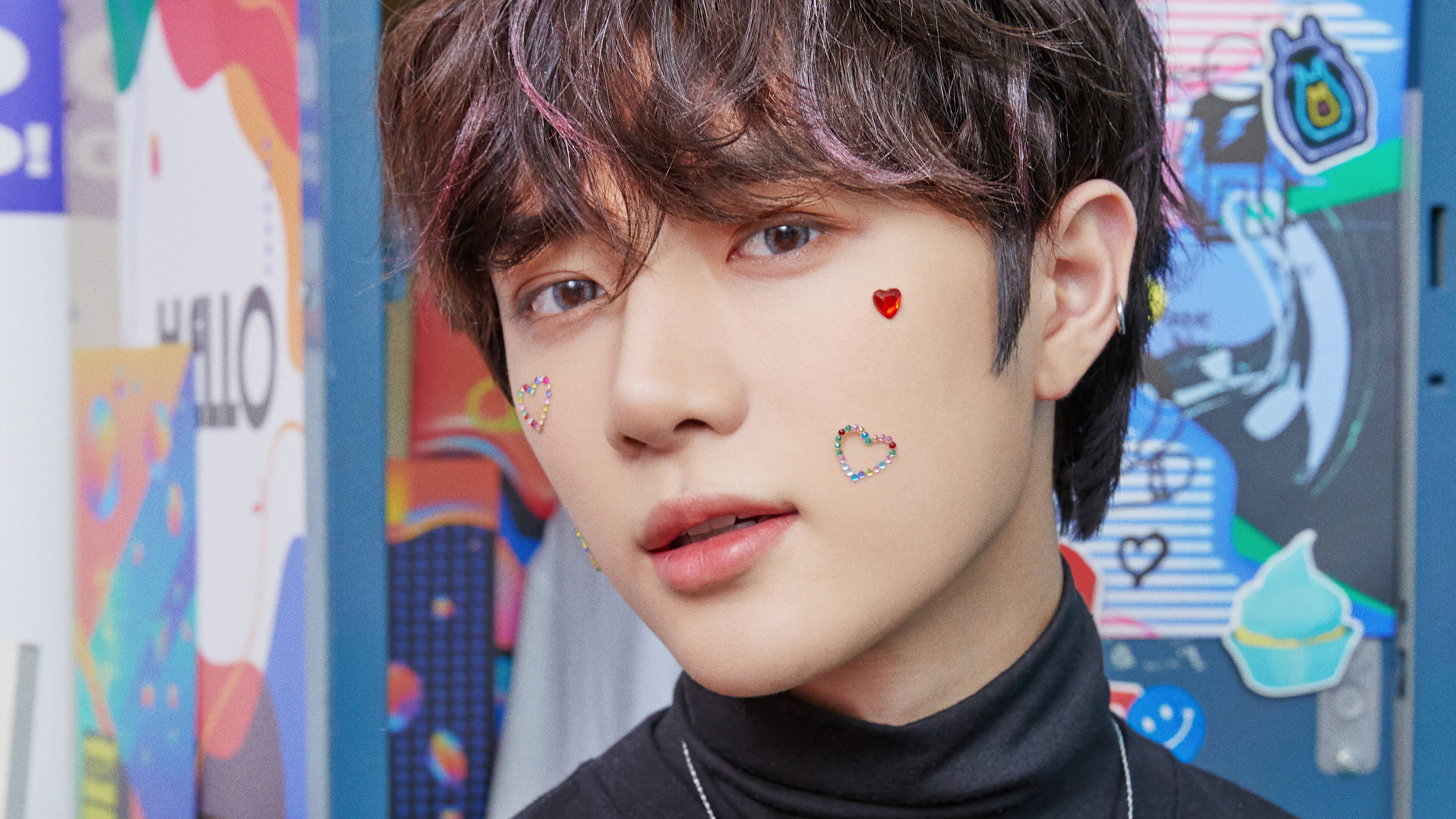 Tomorrow X Together《Blue Hour》Beomgyu 壁紙 — 一位年輕男子擁有色彩繽紛的頭髮和閃閃發光的心形貼紙，柔和地凝視著充滿活力的塗鴉牆。