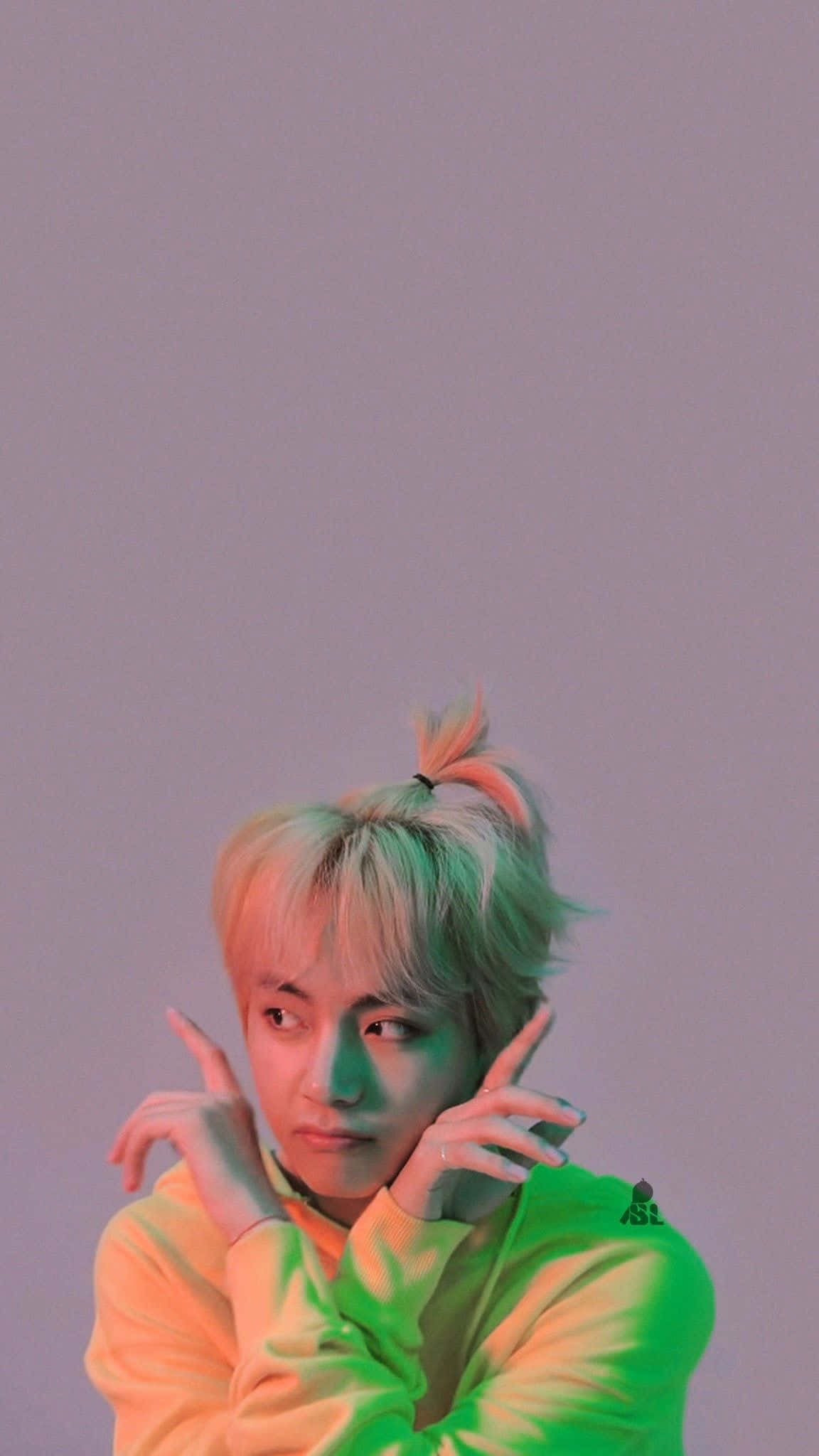 Taehyung Cute 桌布 壁紙 — 一位年輕男子梳著粉彩髮色的高髻，在柔和的紫色背景下，於霓虹綠和橙色燈光中擺姿勢。