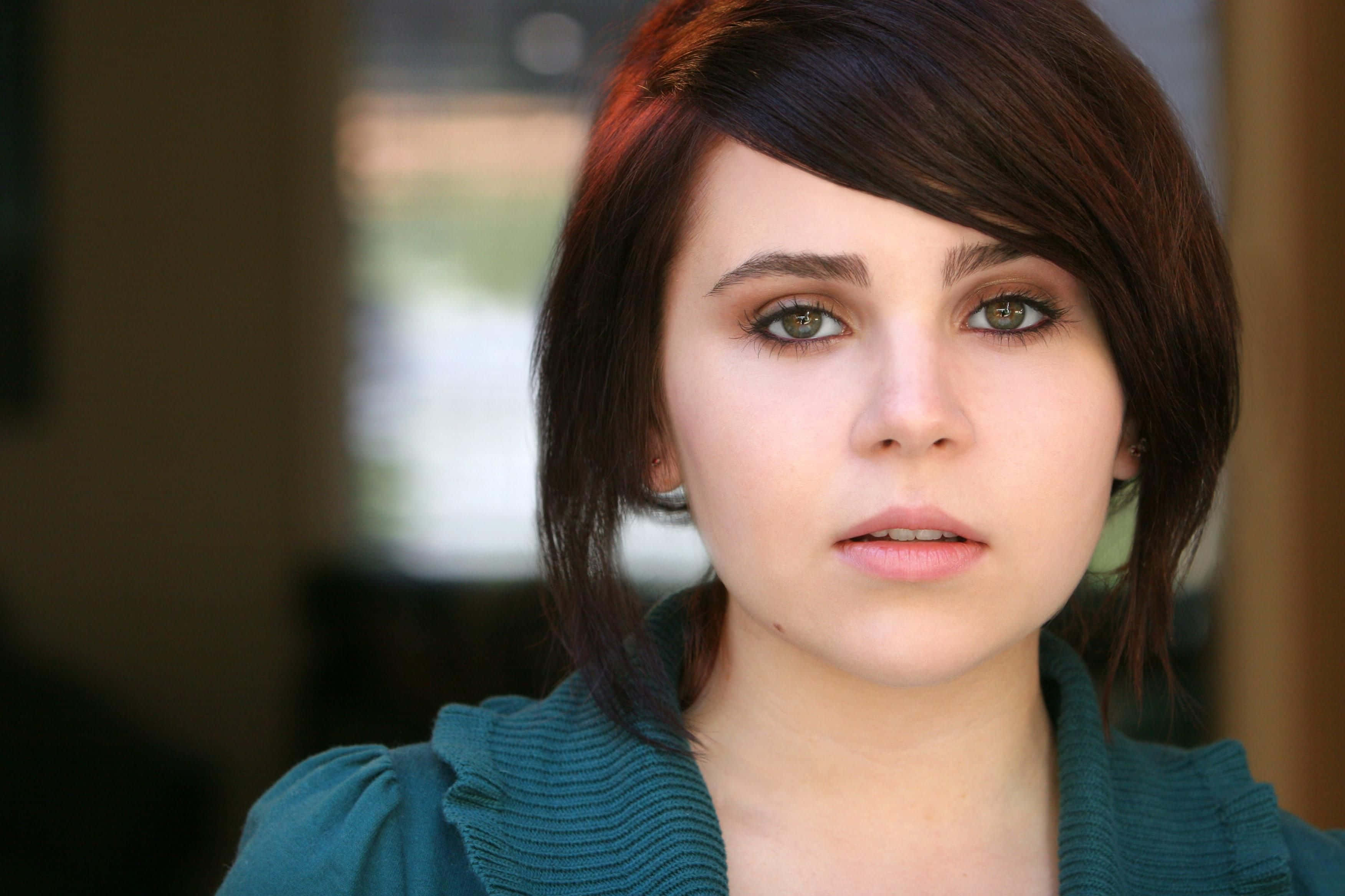 Mae Whitman 桌布 壁紙 — 一位年輕黑髮綠眼女性穿著青綠色羅紋上衣的特寫肖像。