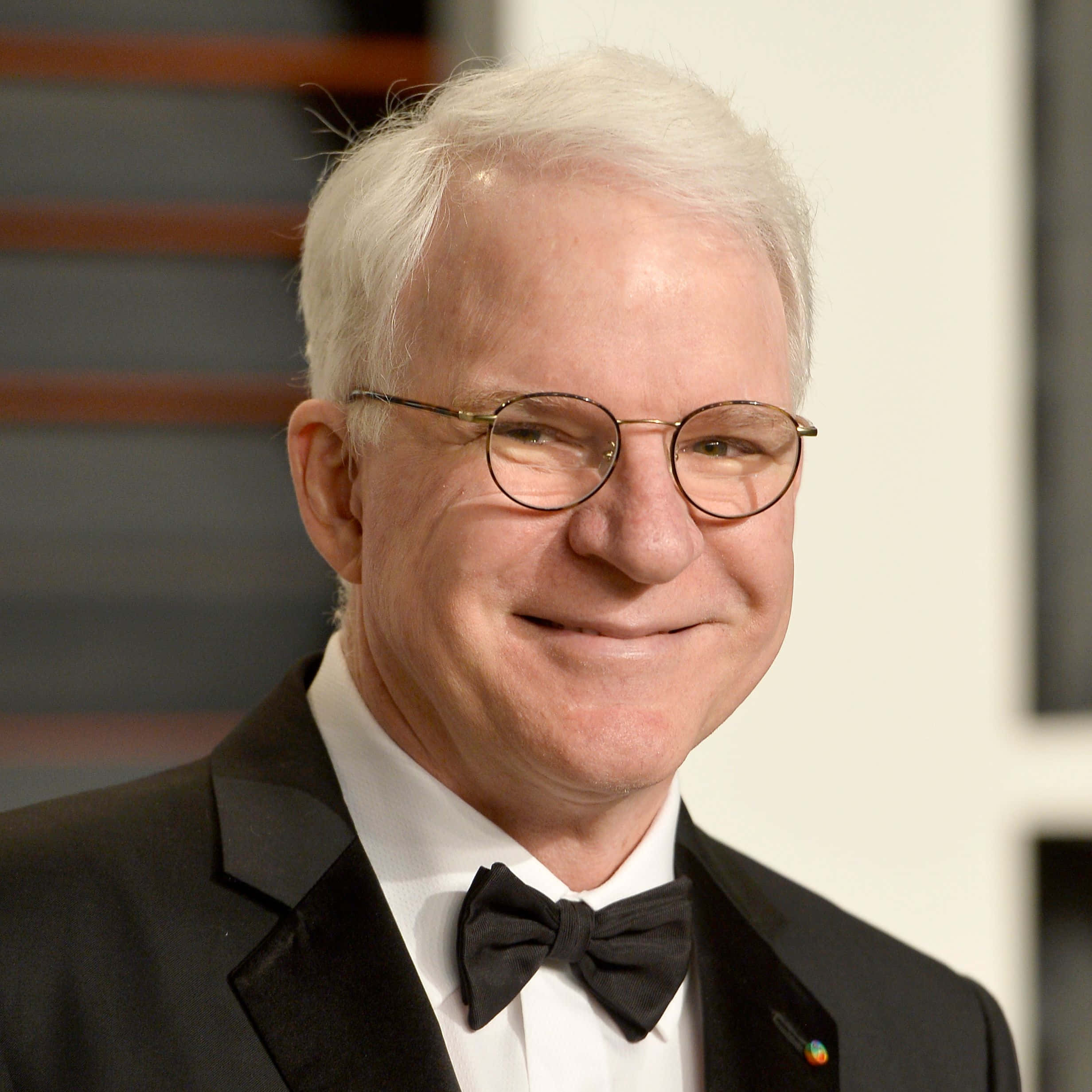 steve martin 桌布 壁紙 — 一位微笑的年長男士特寫肖像，白髮、圓框眼鏡，身穿黑色燕尾服和領結。